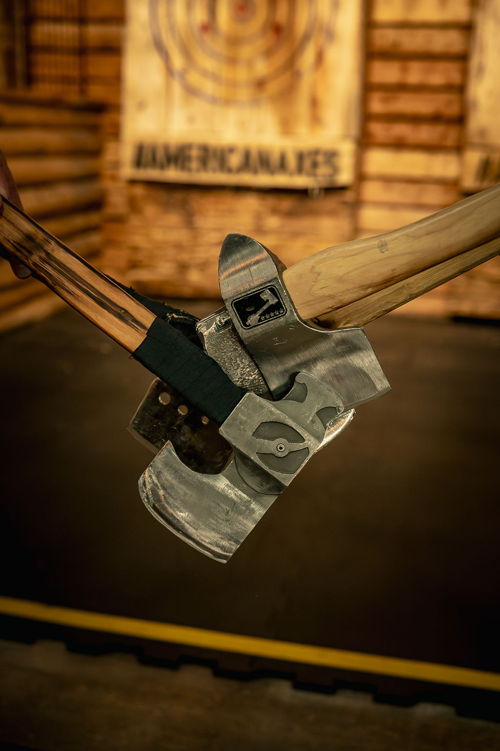 Close-up of a mechanical axe with a wooden handle and metal head, in a wooden indoor setting.