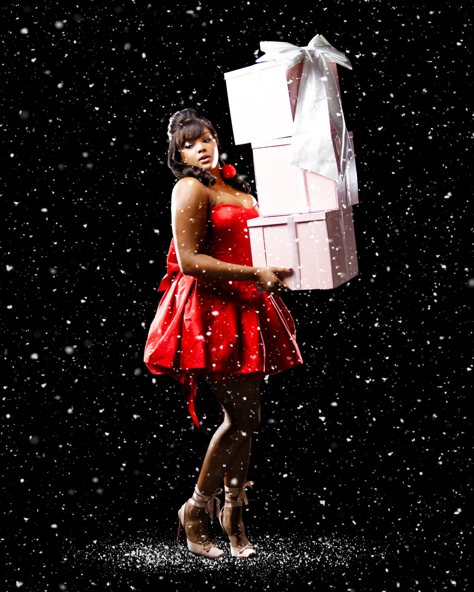 Woman in red dress holding gift boxes against a snowy black background.