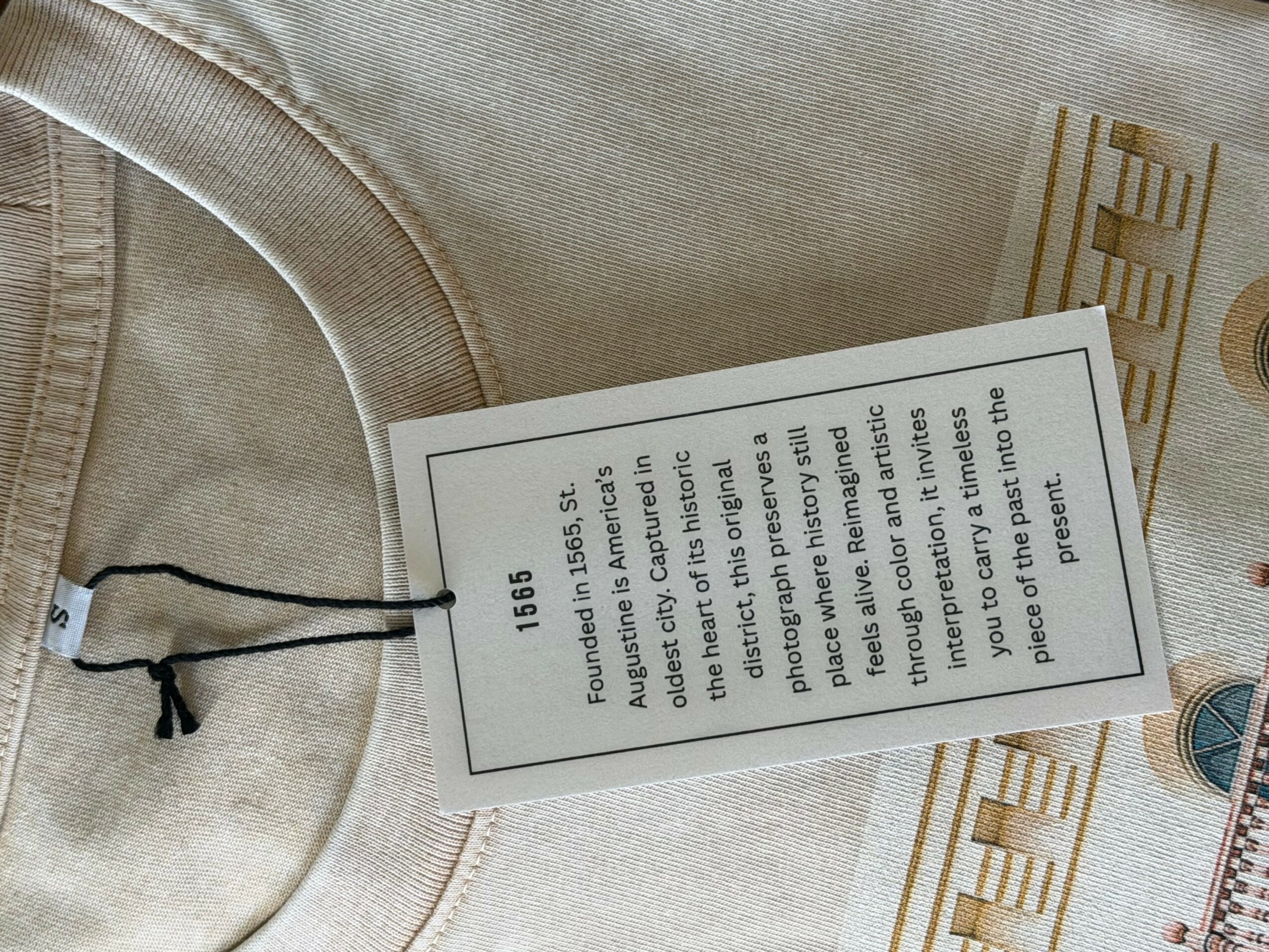 Clothing label attached to a beige garment, with text about fabric and care instructions.