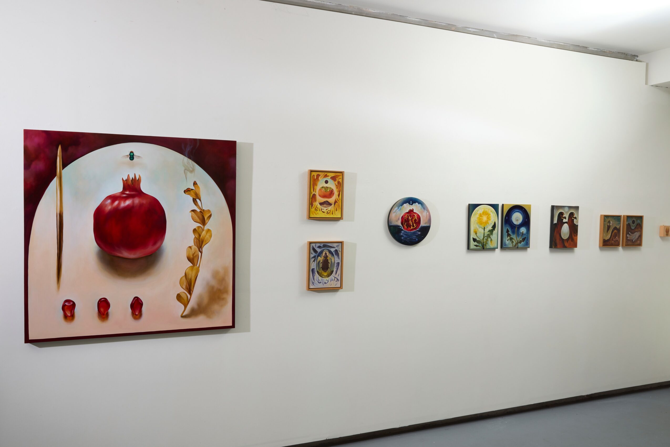 Gallery wall with various small and one large colorful paintings, white wall background, minimalistic setting.