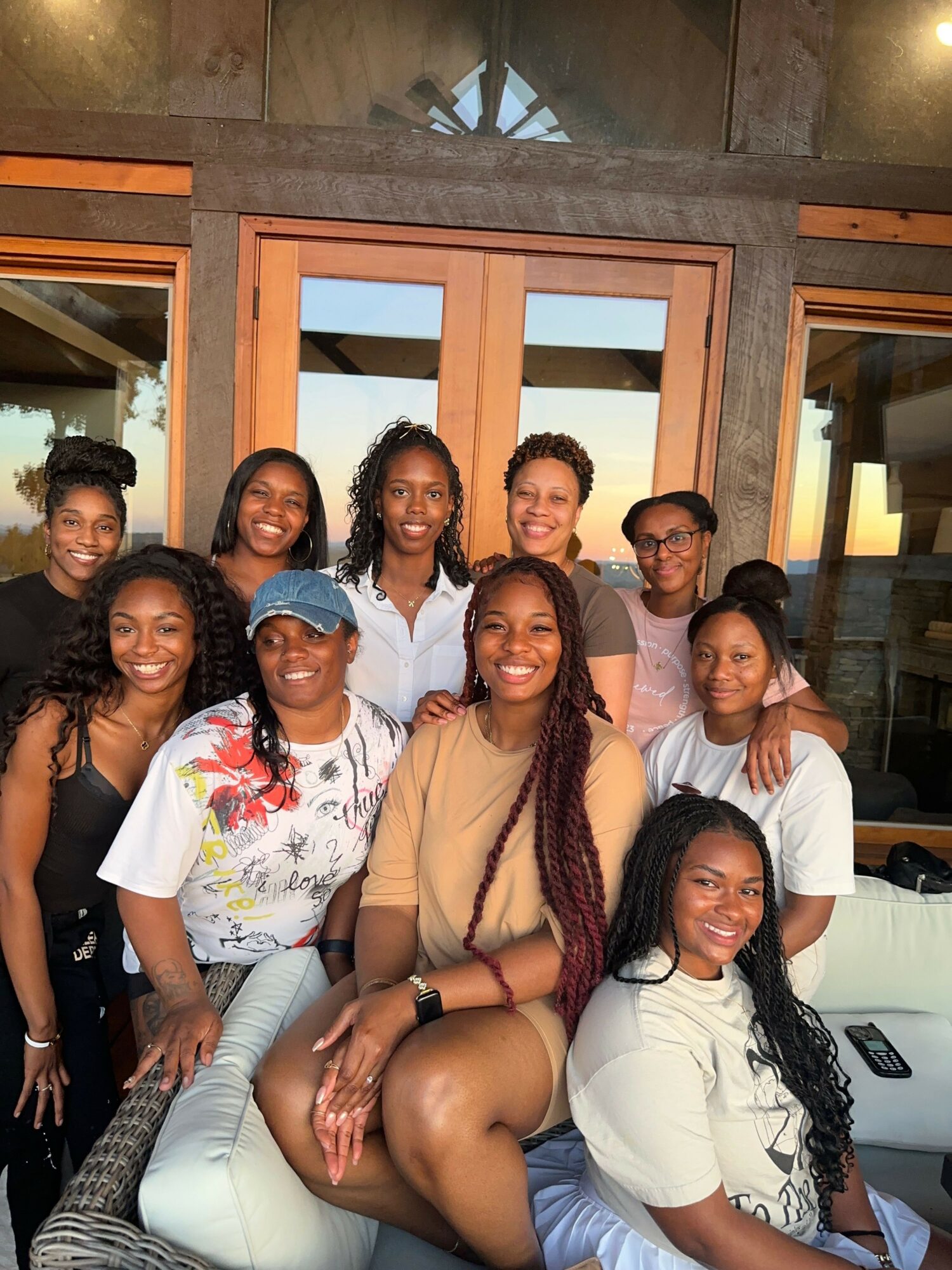 Group of nine people sitting together indoors, smiling and posing for the photo.
