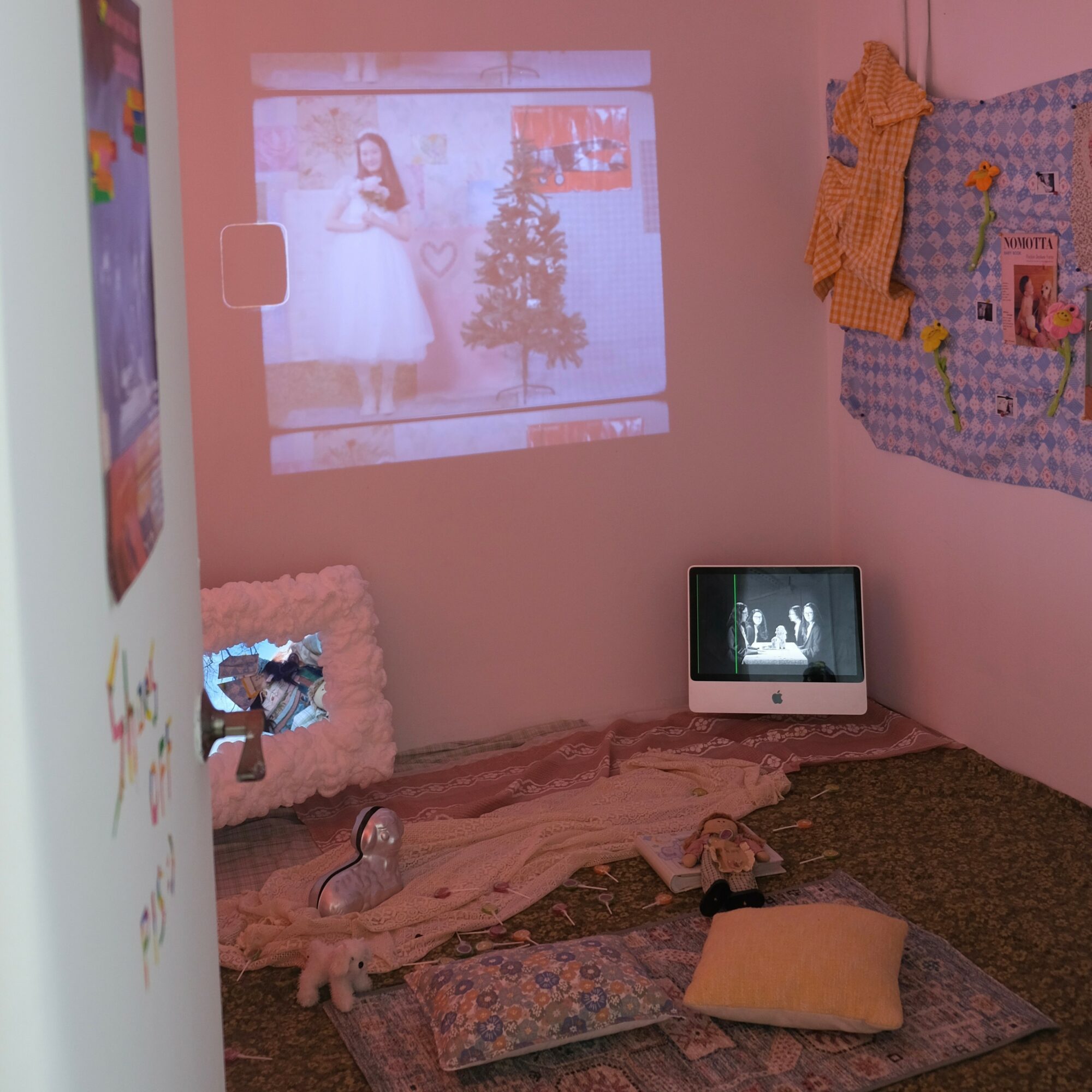 A cozy room with a projected image of a woman in a white dress and a Christmas tree on the wall, a small TV, and cushions.