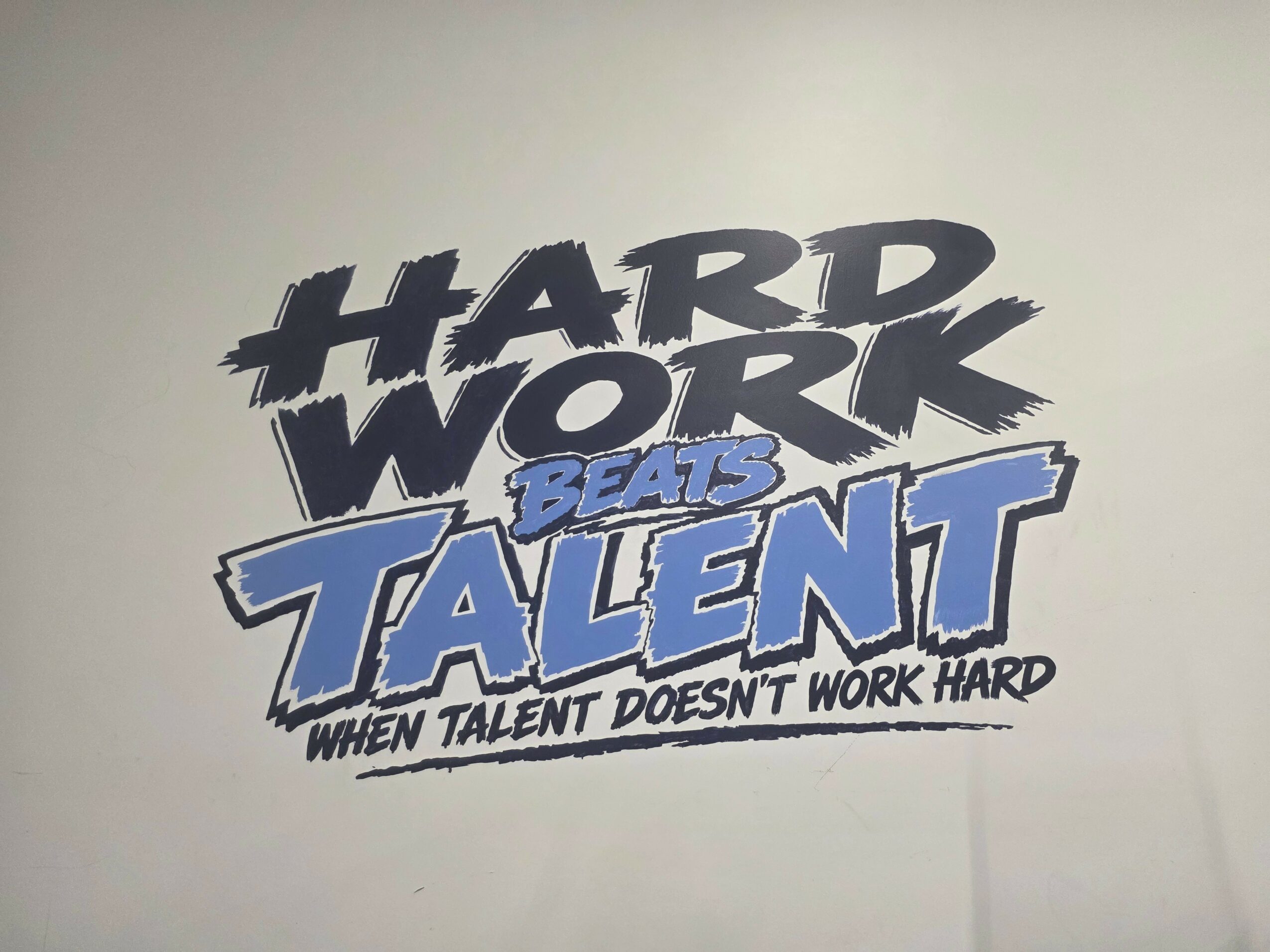 Text on wall reads 'HARD WORK BEATS TALENT WHEN TALENT DOESN'T WORK HARD'.