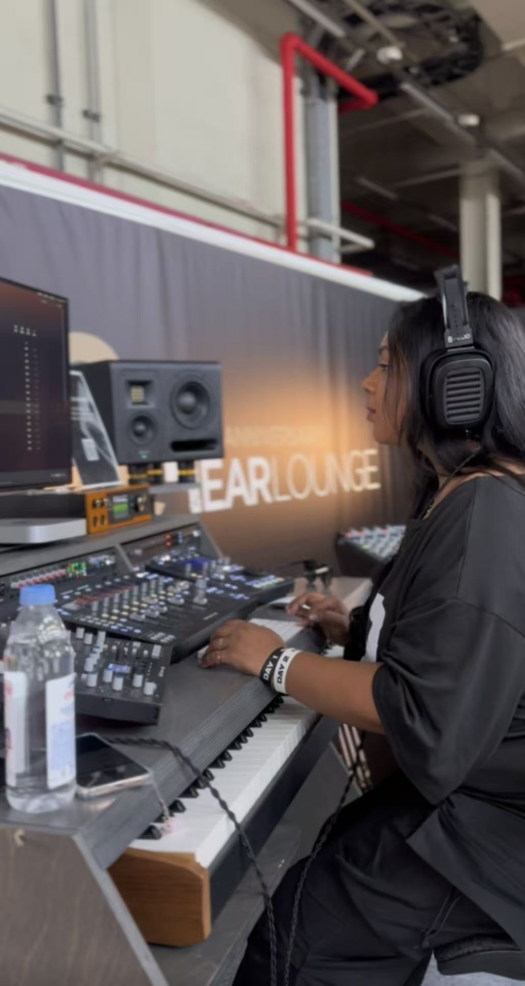 Person wearing headphones working with audio equipment at a music production station, with a banner reading 'HEARLONE' in the background.
