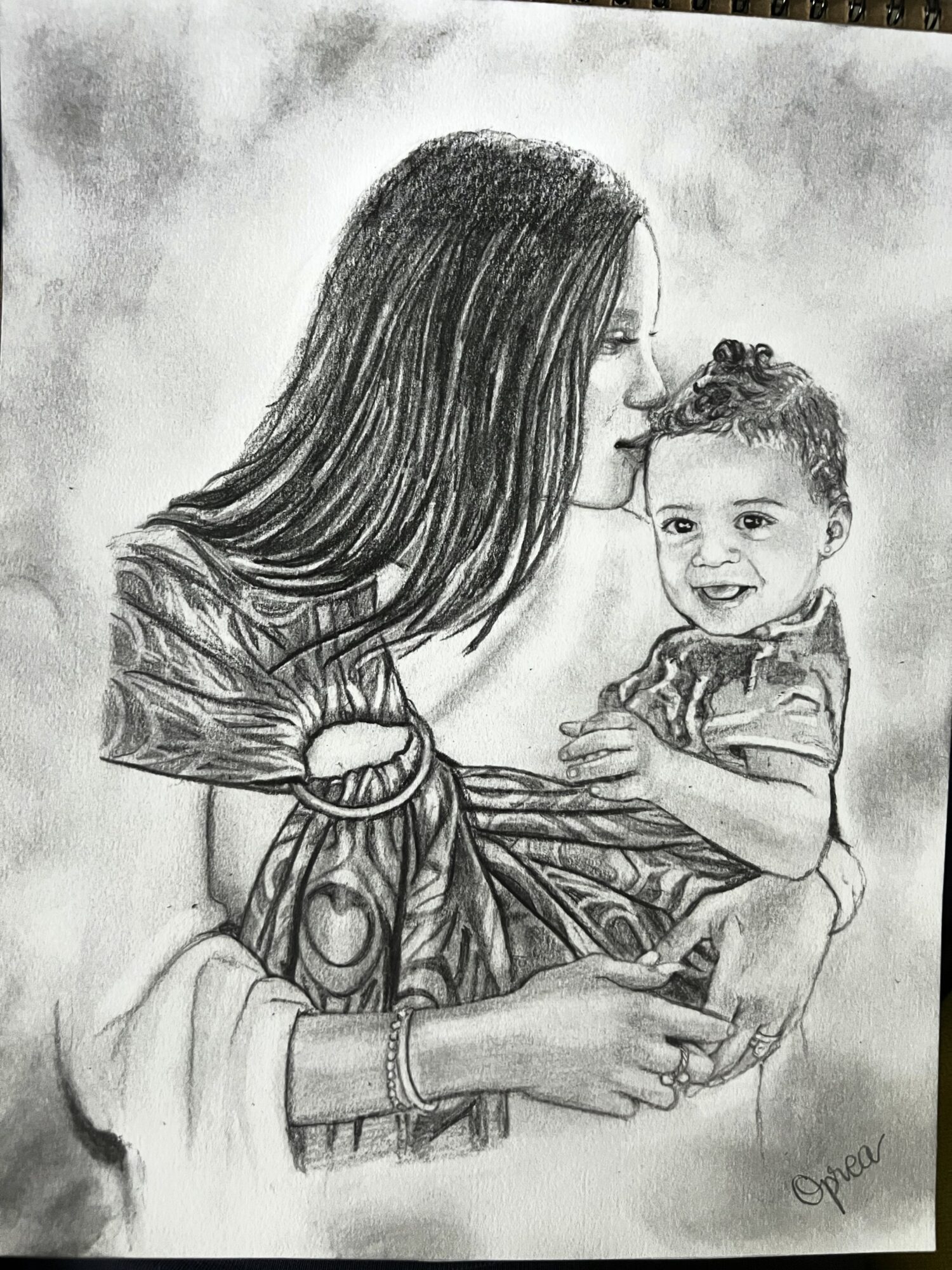 A woman with long hair holding a smiling child, both facing each other, in a detailed pencil sketch.