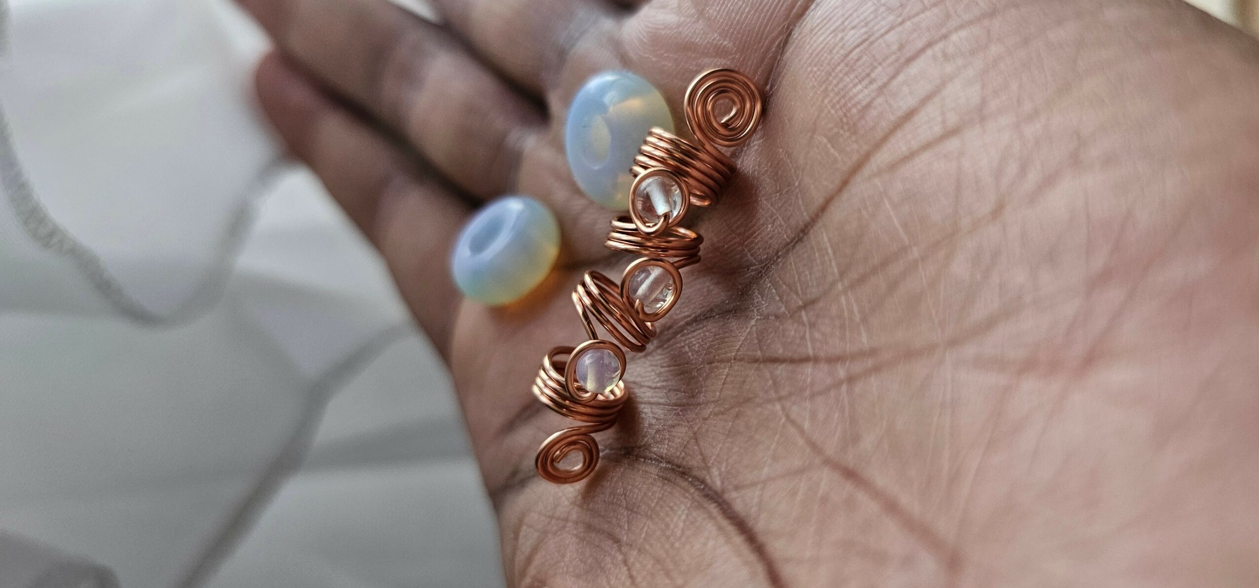 Close-up of a hand with medical electrodes and copper wires attached, skin visible.