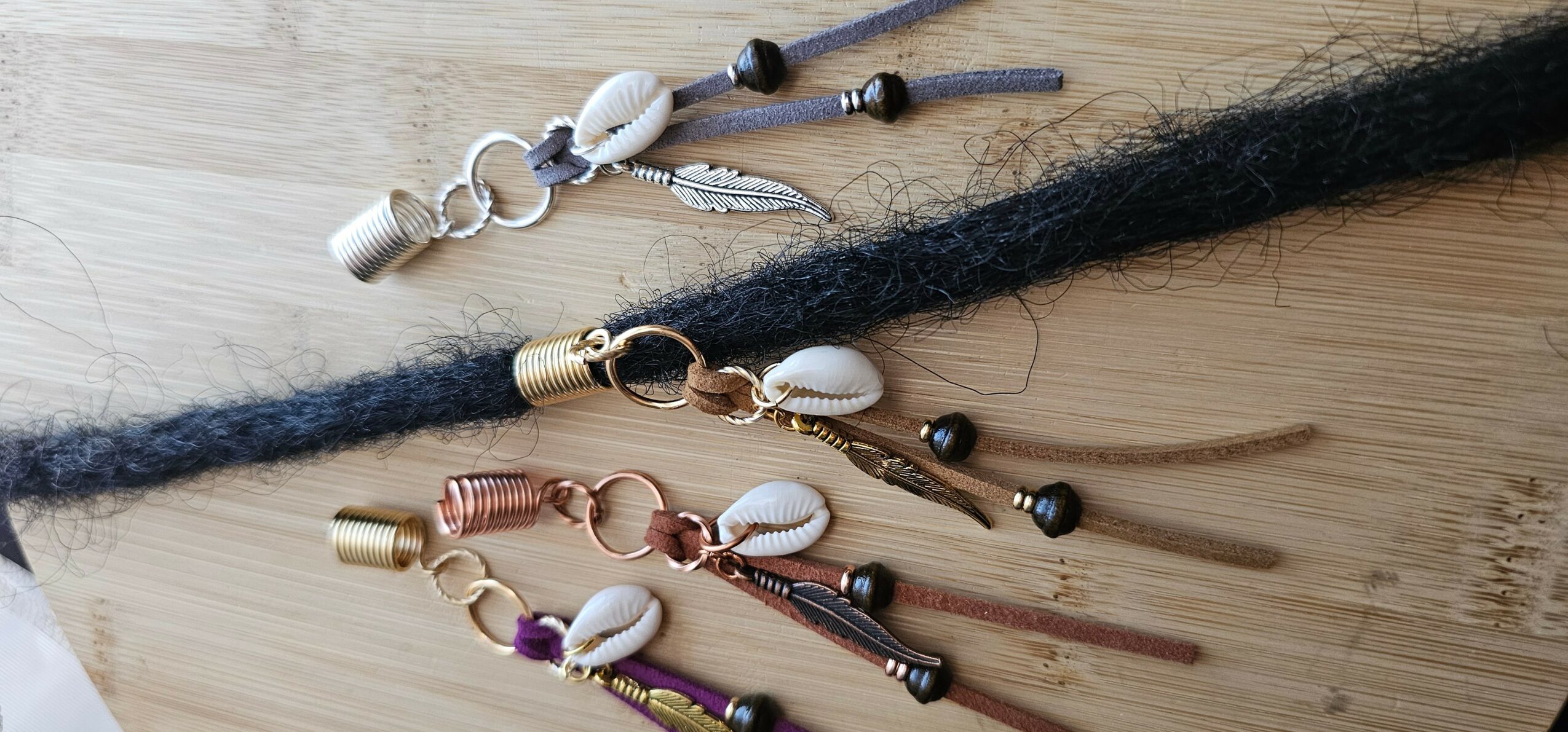 Multiple hair extensions with beads and charms on a wooden surface.