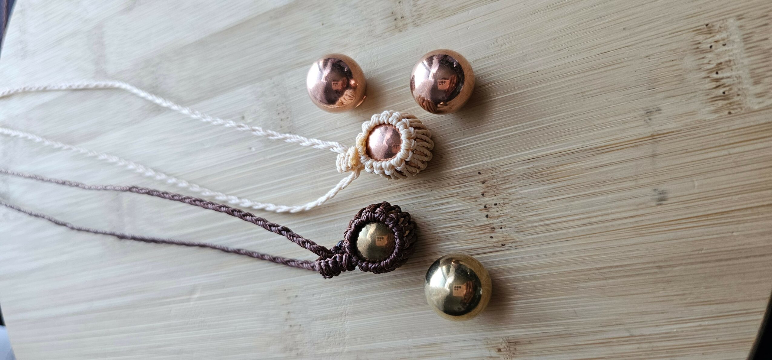 Three necklaces with spherical pendants and three loose spherical beads on a wooden surface.