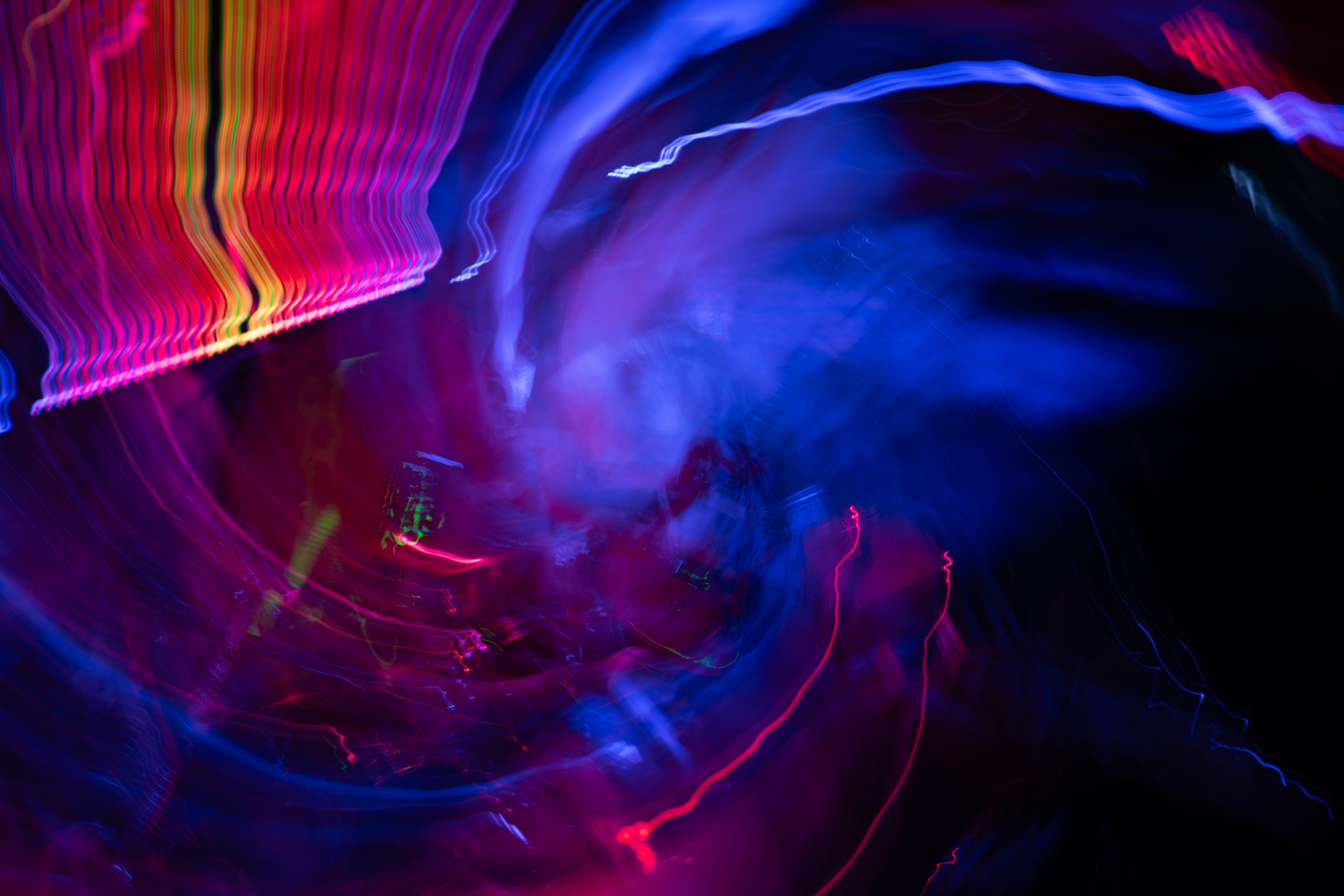 Abstract light trails in red, yellow, blue, and purple create swirling patterns and motion effects.
