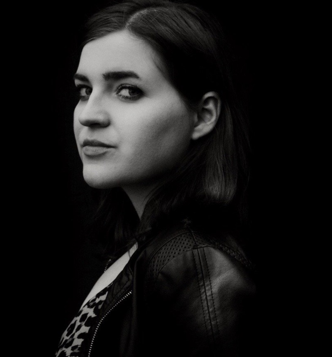 Black and white portrait of a woman with dark hair, looking sideways, wearing a leather jacket.