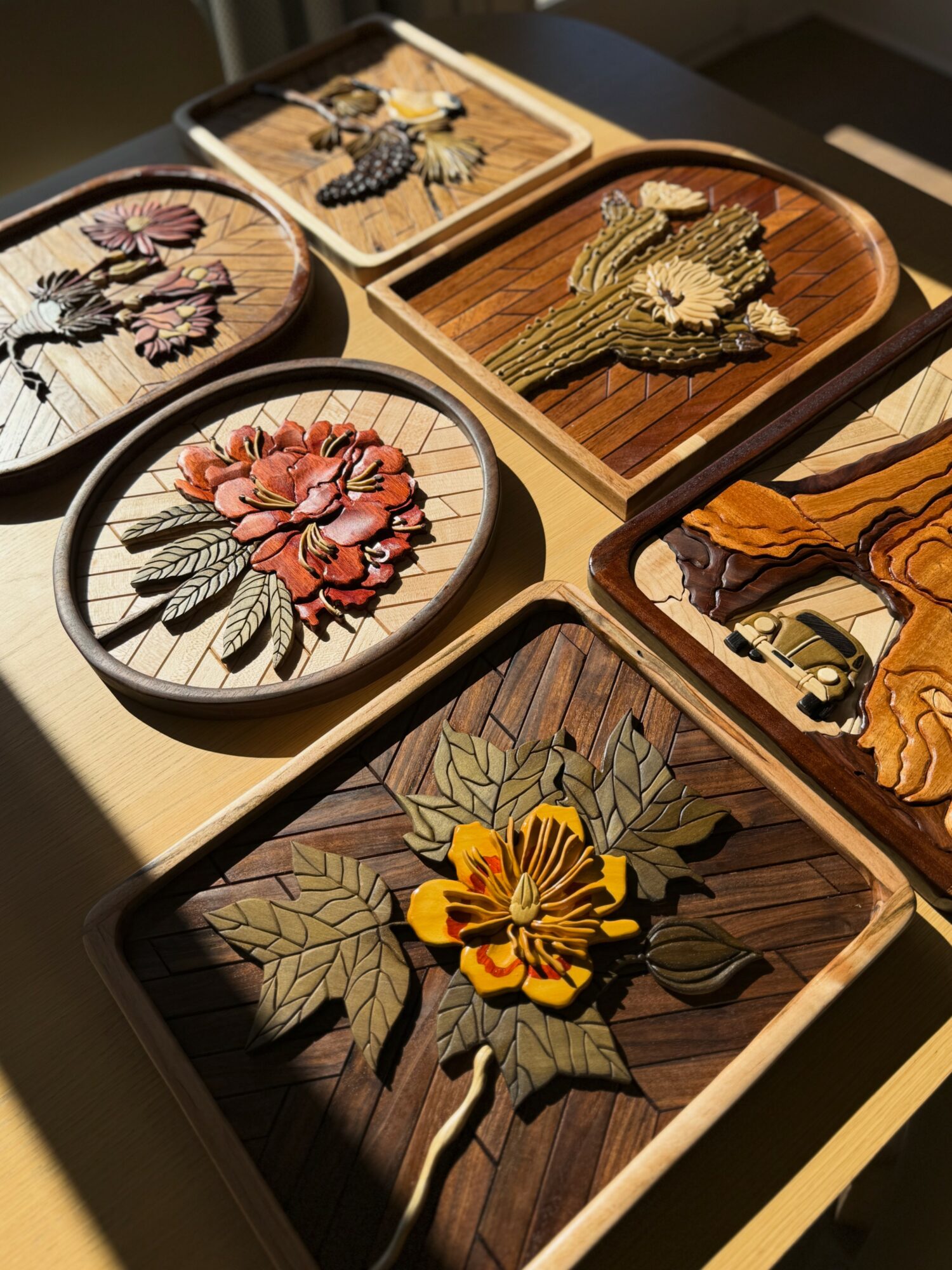 Collection of embroidered floral patches on wooden trays, featuring various flowers with detailed stitching and colorful designs.
