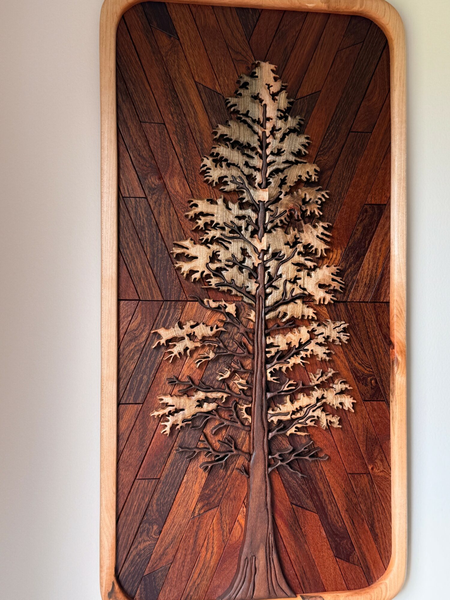 Decorative wooden tree design on a wooden floor, framed by a rounded rectangular border.