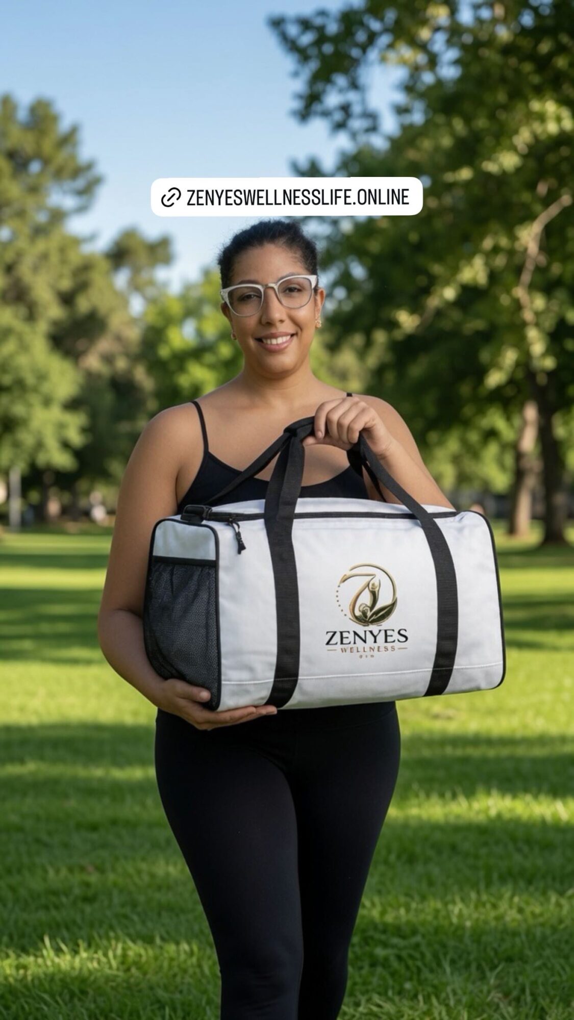 Woman holding a Zenyés wellness bag outdoors in a park with trees and grass, smiling, wearing glasses and athletic clothing.