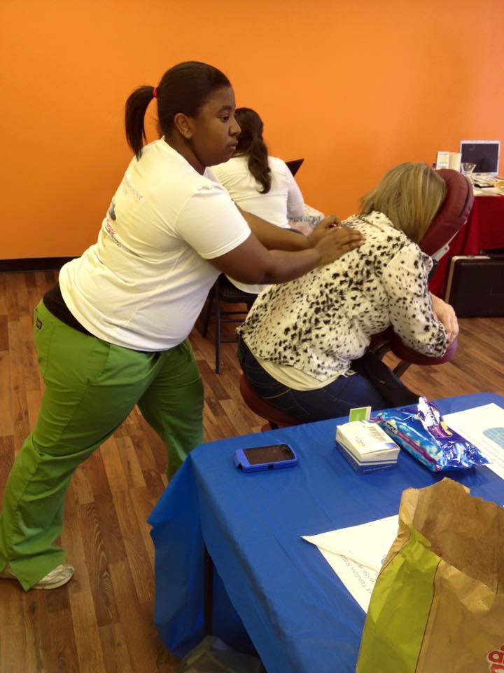 Two women are at a table, one leaning over and the other sitting with her head down, in a room with orange walls.