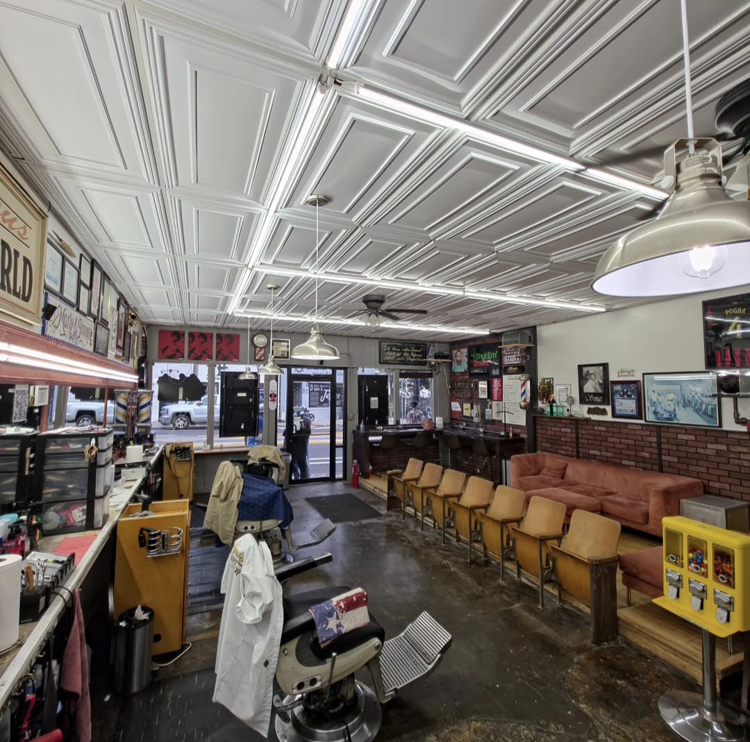 Interior of a vintage-style cafe with chairs, a counter, and decorative wall art, viewed from the entrance.