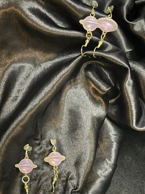 Pink and gold jewelry on black satin fabric, with the jewelry arranged diagonally.
