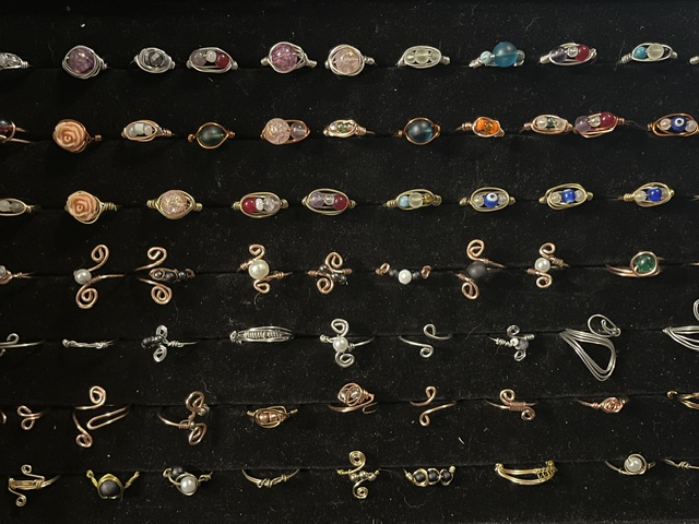 Display of various jewelry pieces, including rings and earrings, arranged on black background.