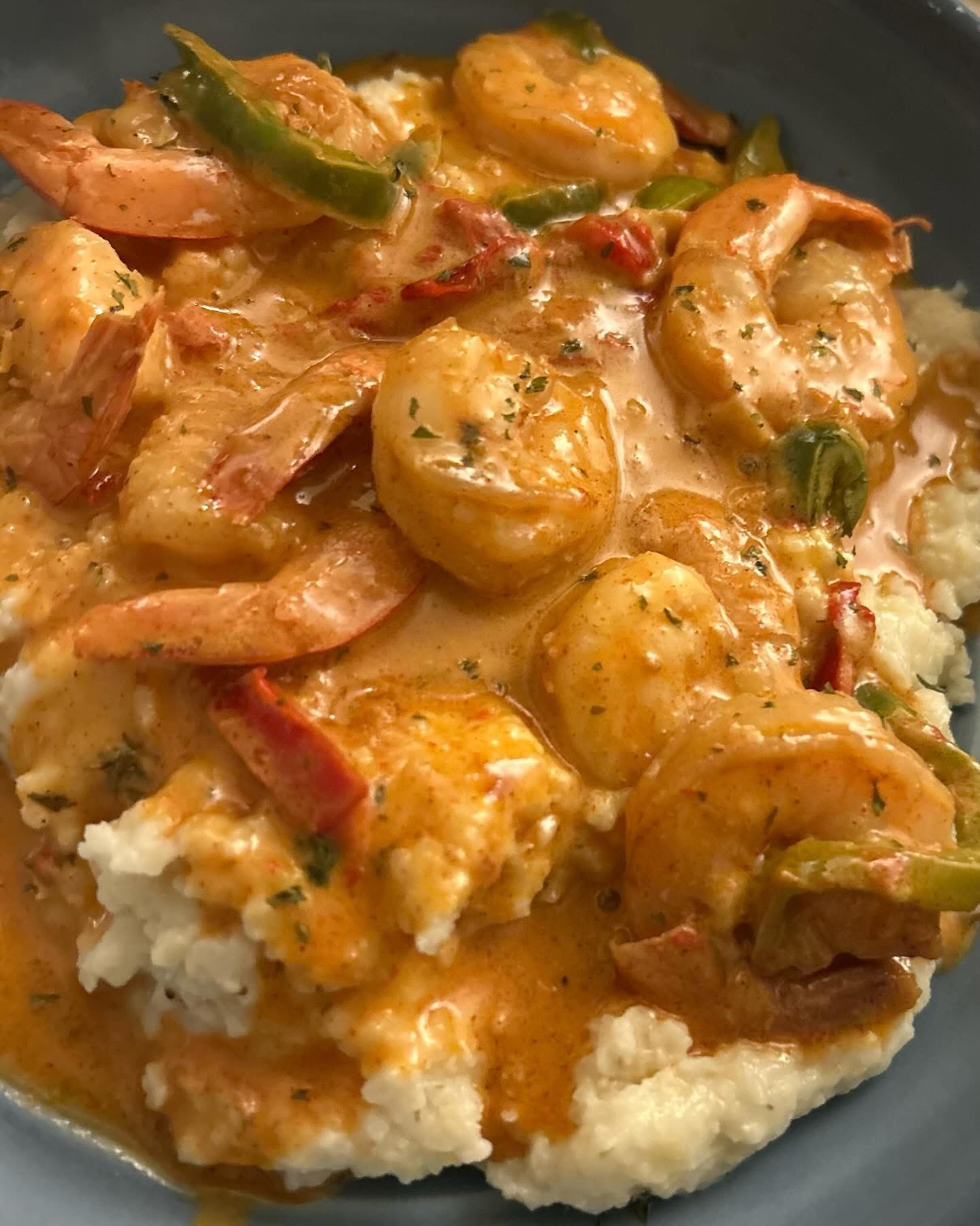 Shrimp and vegetables in creamy sauce served over mashed potatoes, garnished with herbs.