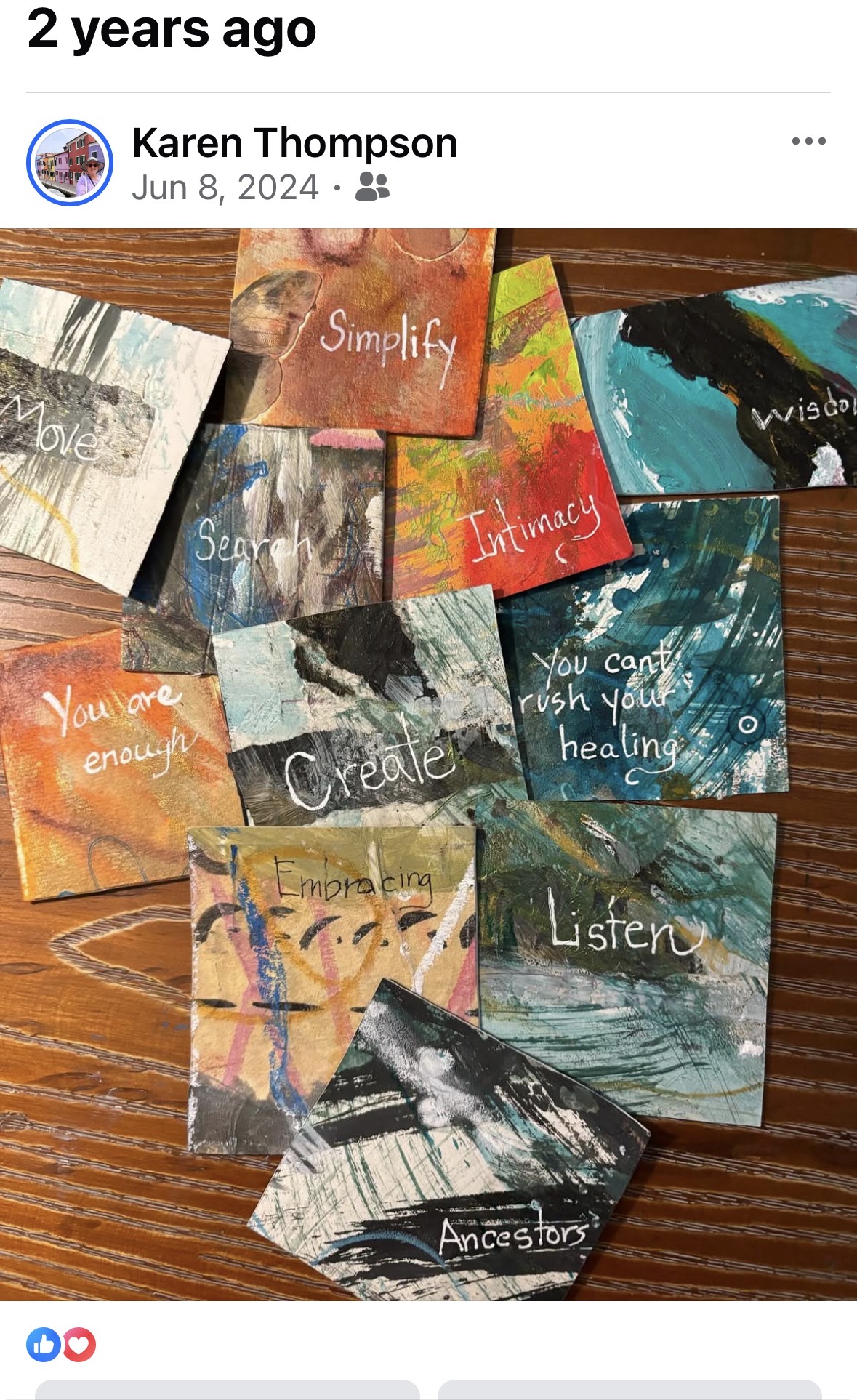 Collection of small, colorful painted cards with words like 'Simplify,' 'Uniqueness,' and 'Listen' on a wooden surface.