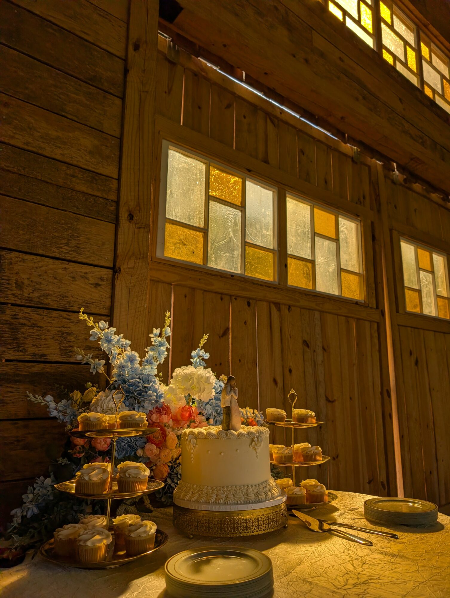 Cake with flowers and desserts on a table inside a wooden building with stained glass windows.