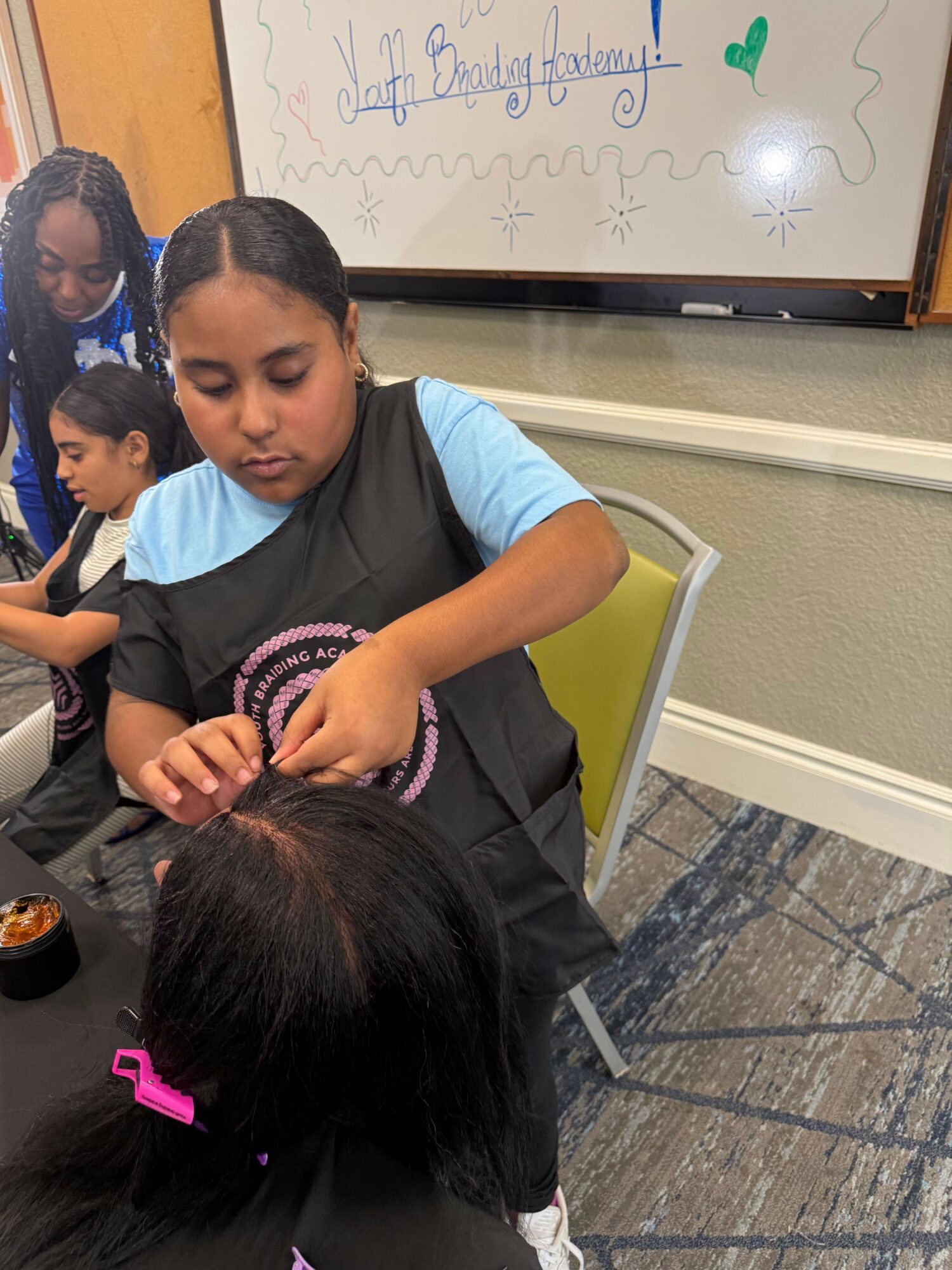 Two children sitting on the floor, one with long black hair and the other with short hair, engaging closely.