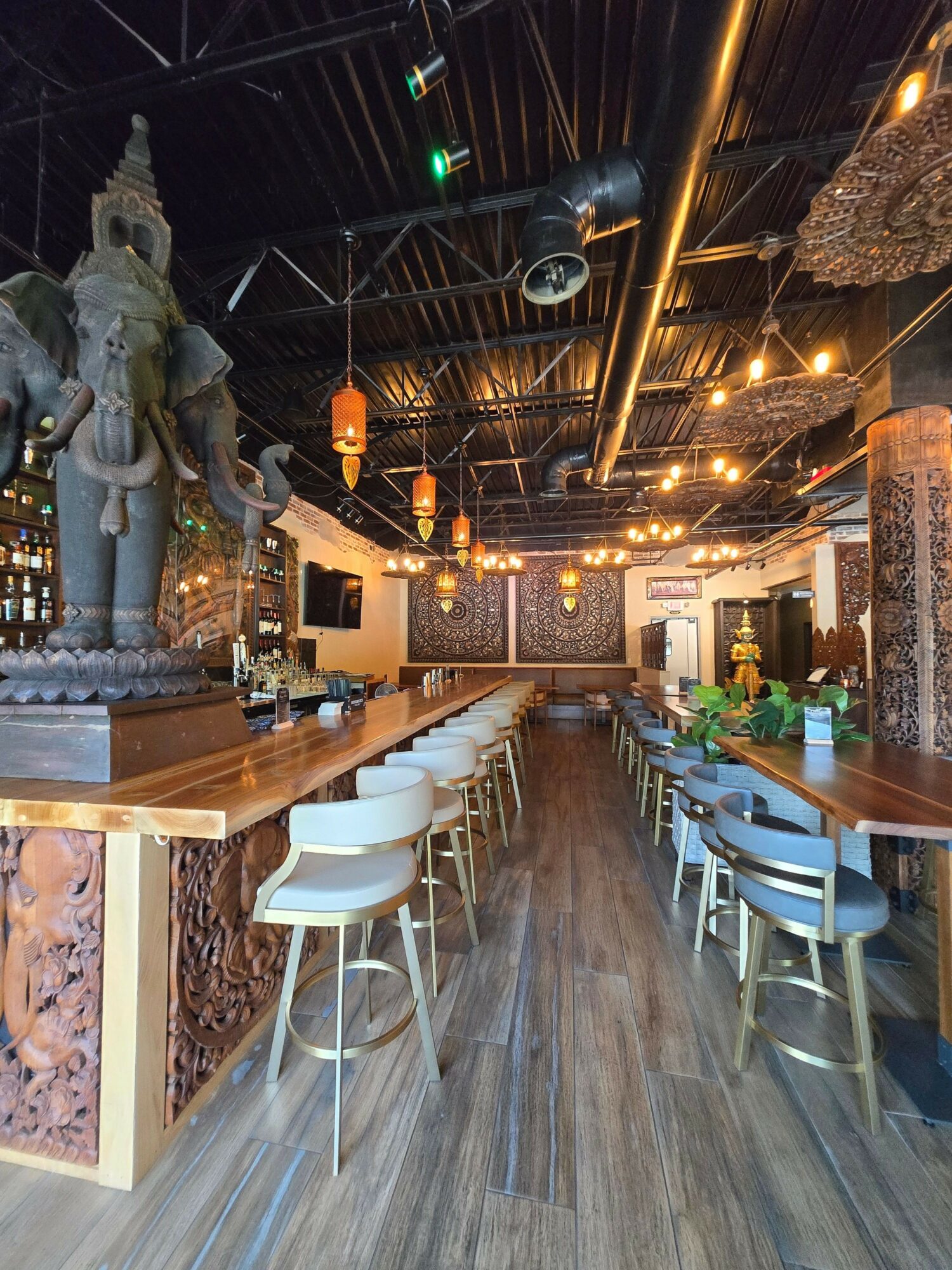 Interior of a restaurant or cafe with wooden flooring, tables, chairs, and decorative lighting, viewed from the entrance.