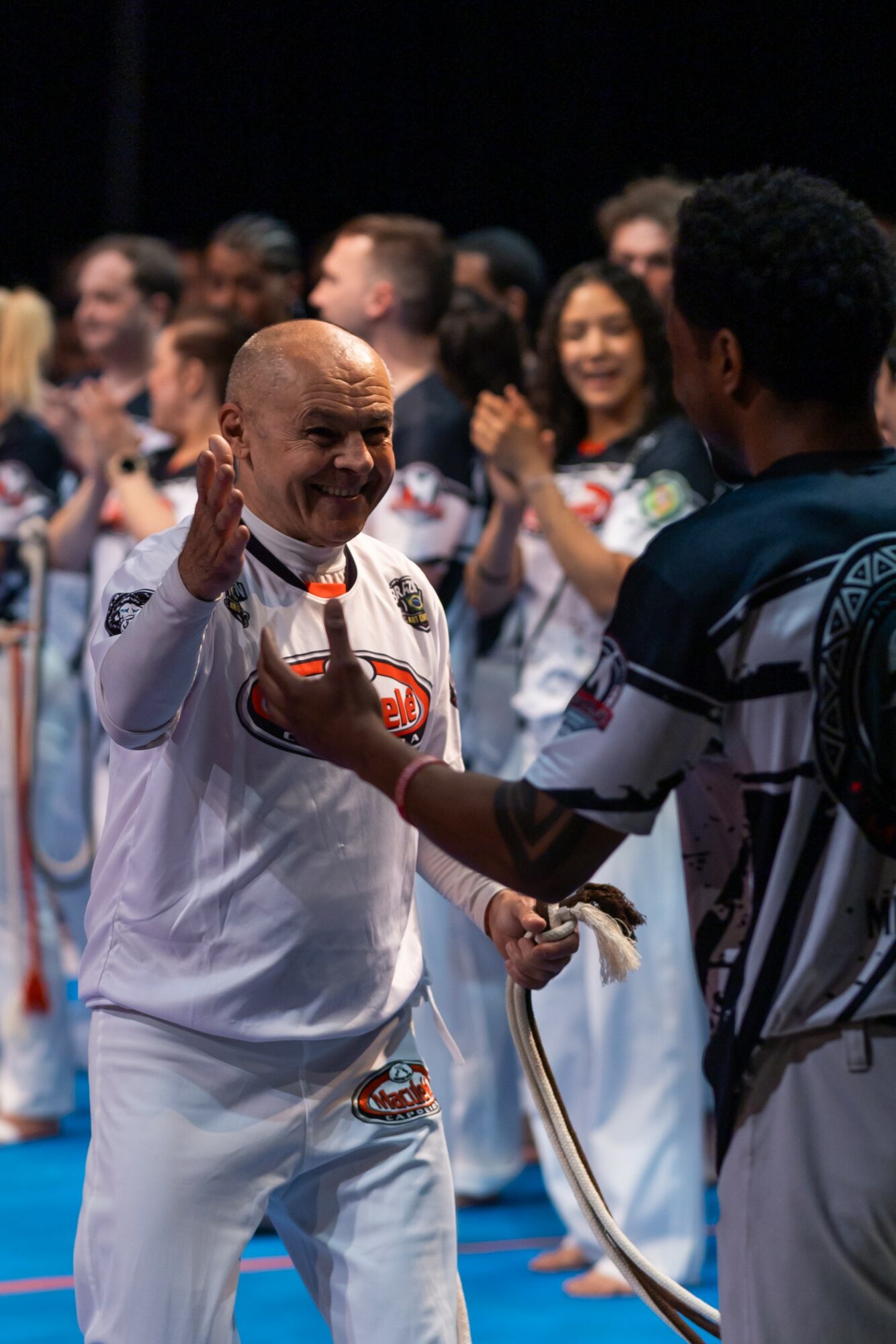 A group of people, including a man in a white sports jersey, celebrating and smiling at an event.