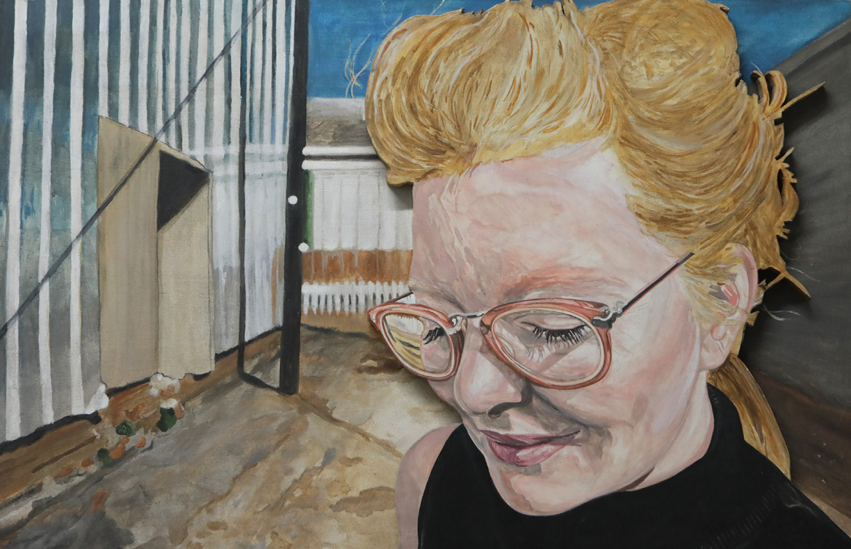 Close-up of a woman with glasses and blonde hair, smiling, with a construction site background.