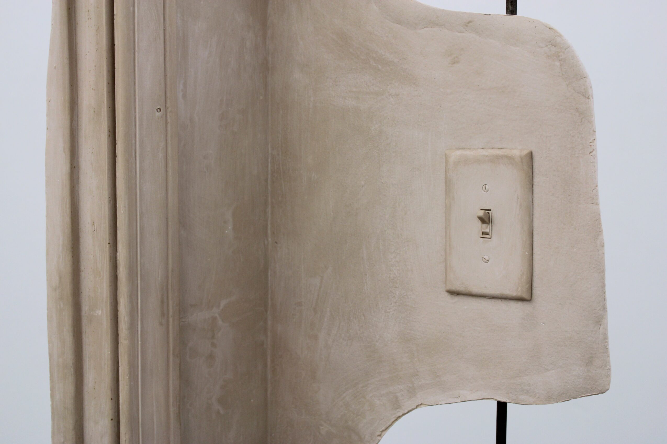 Close-up of a wall with a light switch, showing a textured surface and a rounded corner.