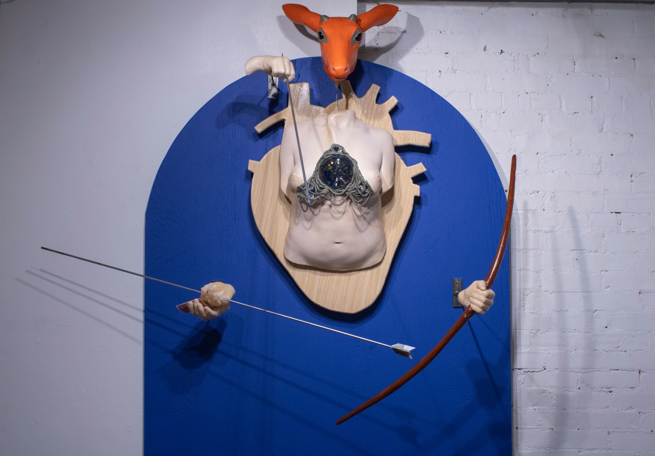 Mounted animal skull with a mask, a bow, and a mask with a fox head, displayed on a blue background.