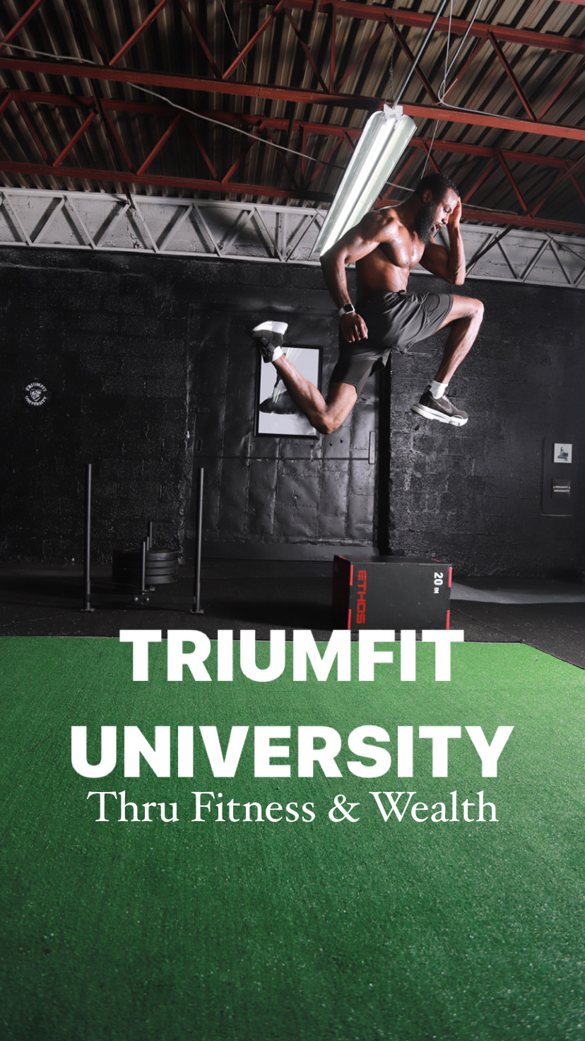 Person jumping in gym with TRIUMFIT UNIVERSITY sign, green floor, black wall, ceiling lights, and industrial ceiling.