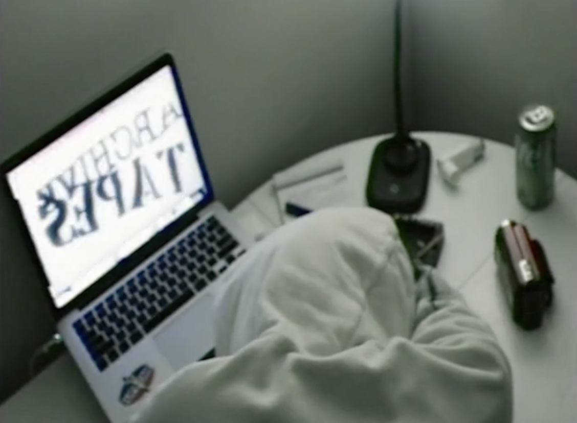 Person sitting with legs crossed, using a laptop on a small table with a soda can and a lighter nearby.