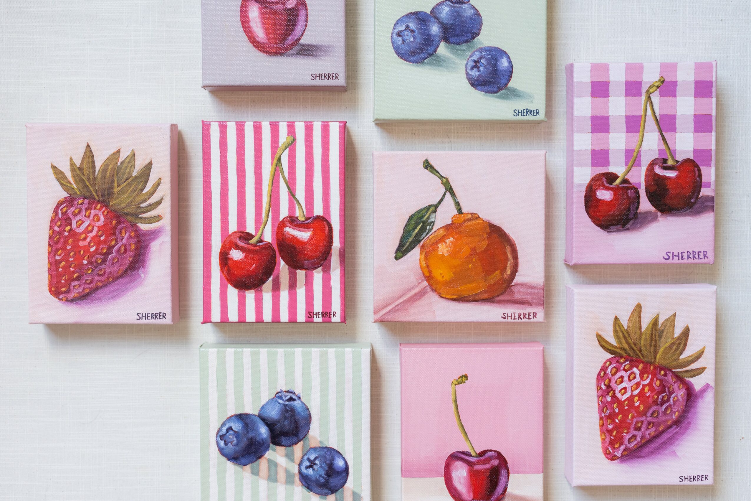Six small cards with colorful fruit illustrations, including strawberries, blueberries, cherries, and an orange, arranged on a white surface.