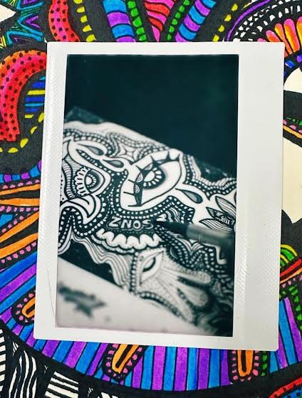 Black and white patterned fabric with intricate designs, partially covered by a white border, on a colorful background.