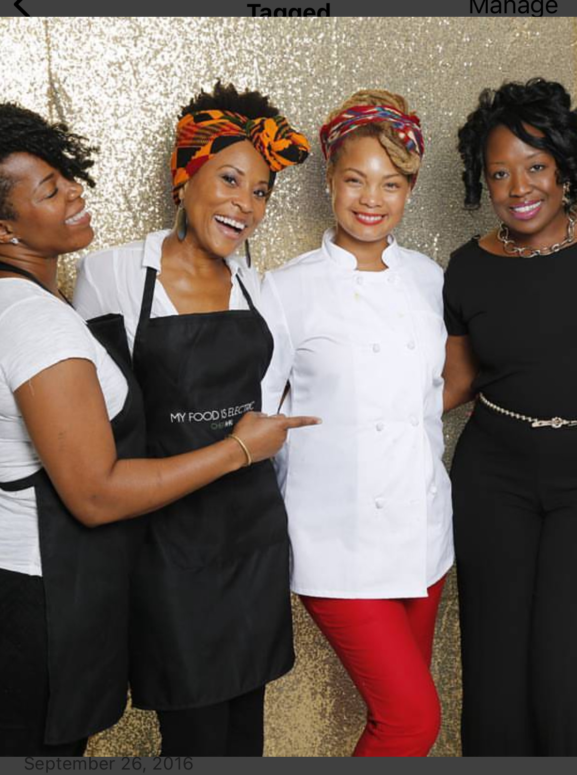 Four women standing together, smiling, with a gold glitter background, one wearing an apron, others in chef's attire.