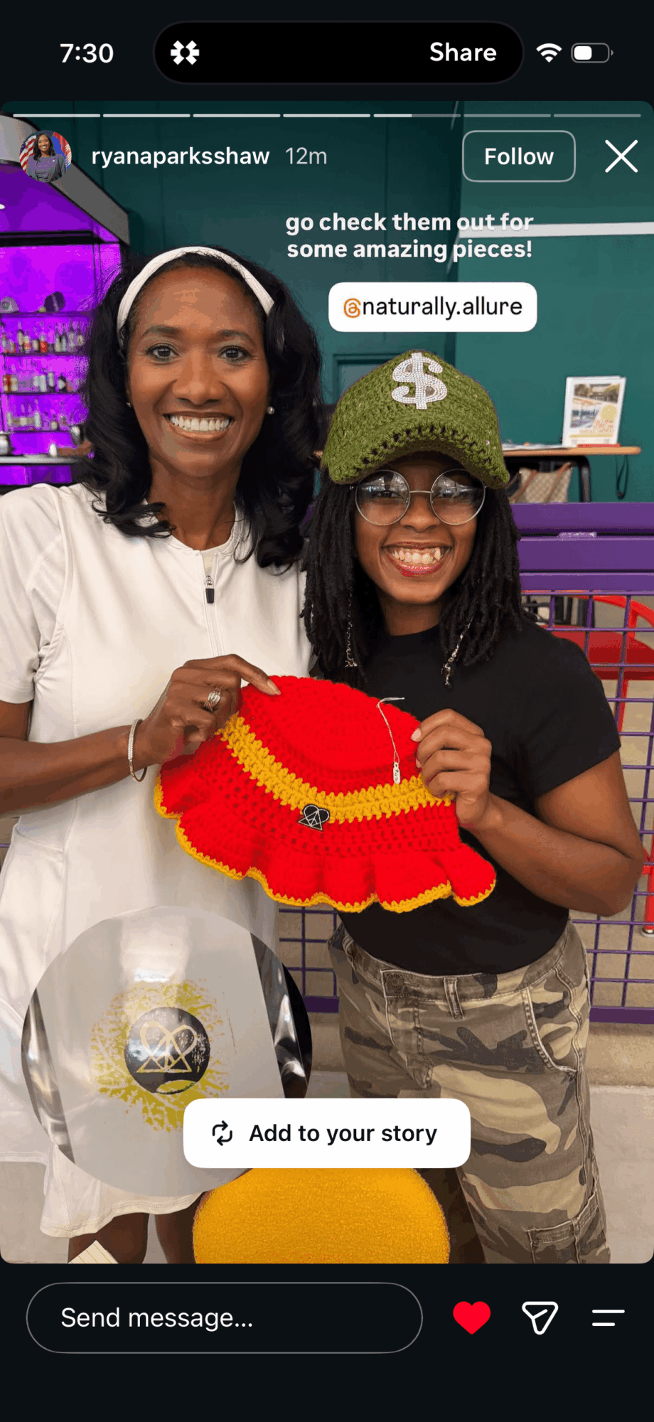 Two women smiling, one holding a red and yellow decorative item, in a colorful indoor setting.