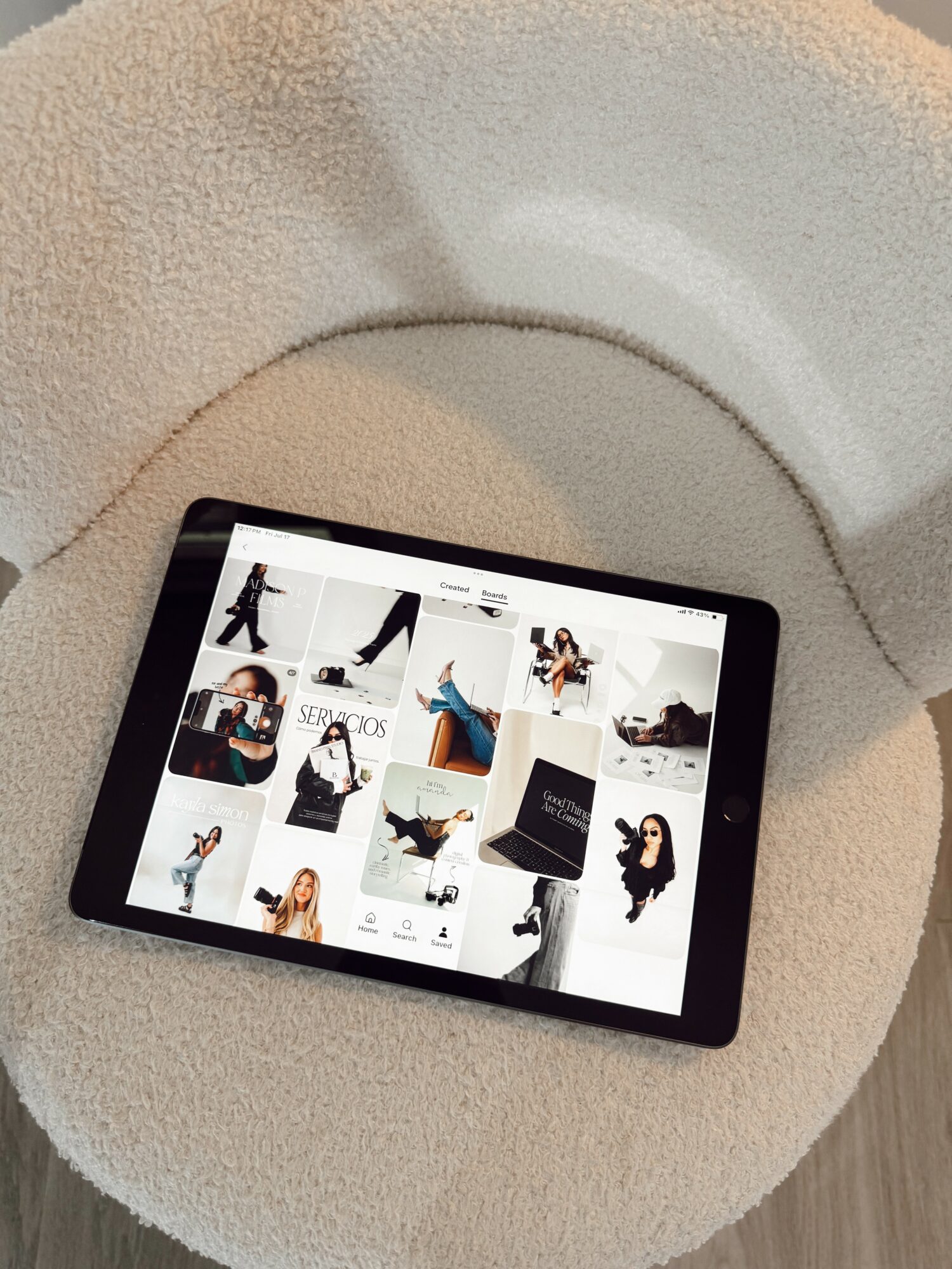 Tablet displaying a grid of fashion images, placed on a white textured surface.