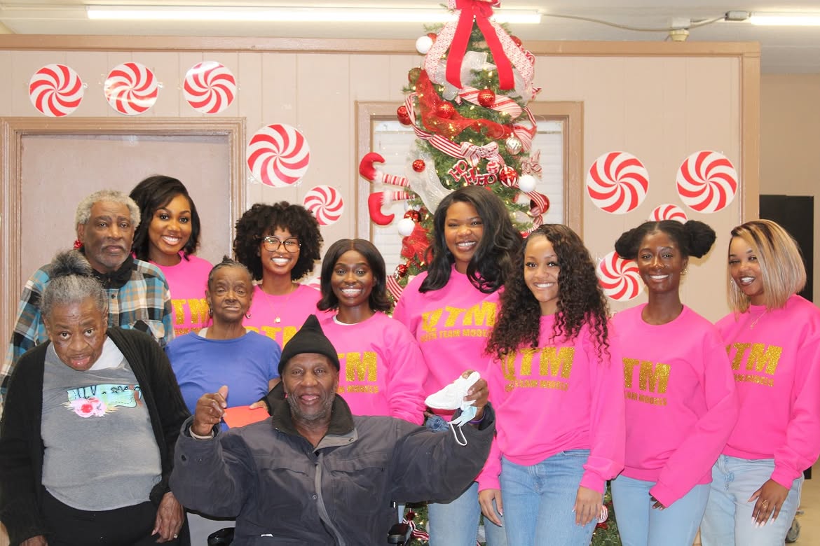 Group of people celebrating Christmas with a decorated tree, peppermint decorations, and festive attire, smiling and posing together.