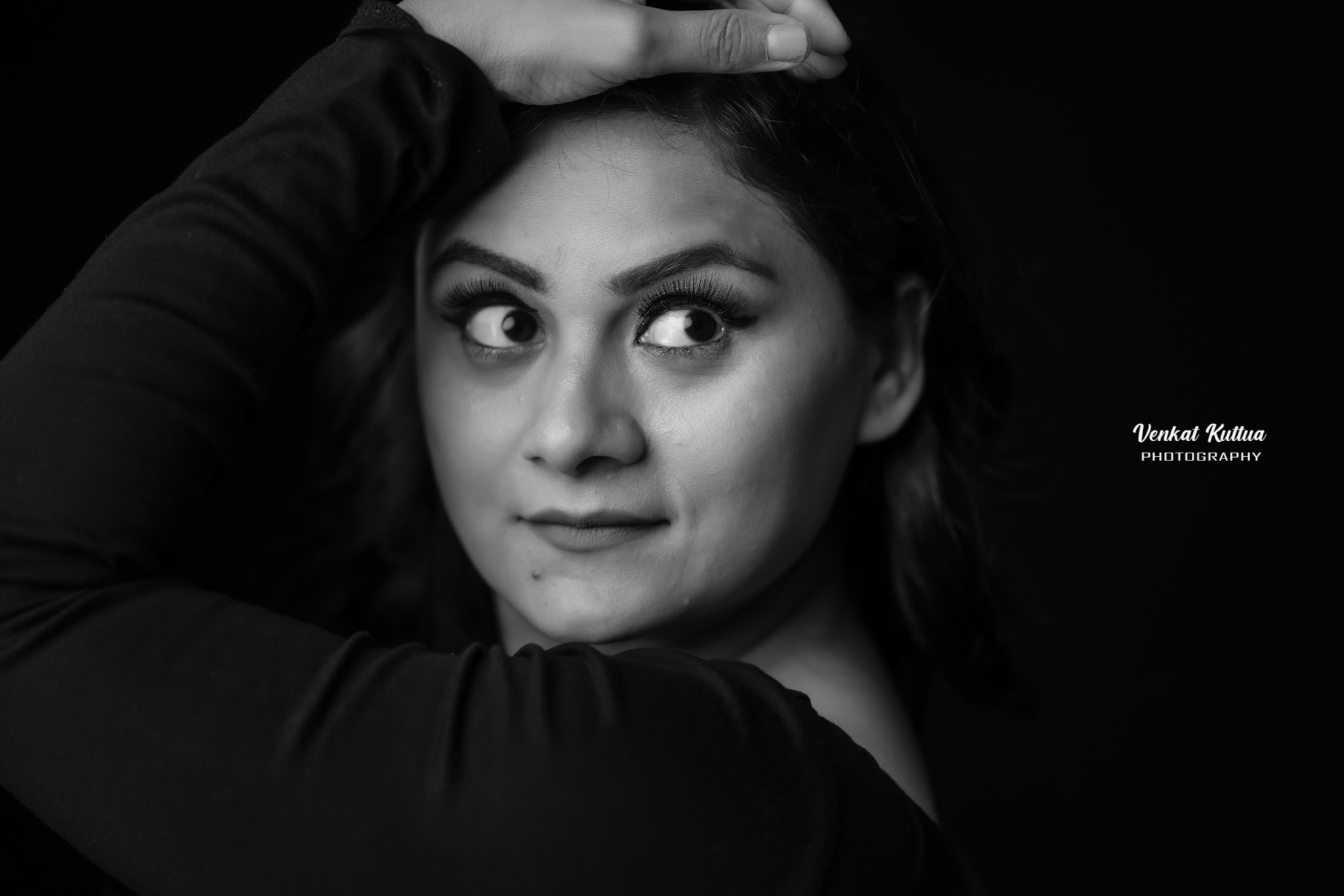 Portrait of a woman with dark hair, looking to the side, hand on her head, in black and white.