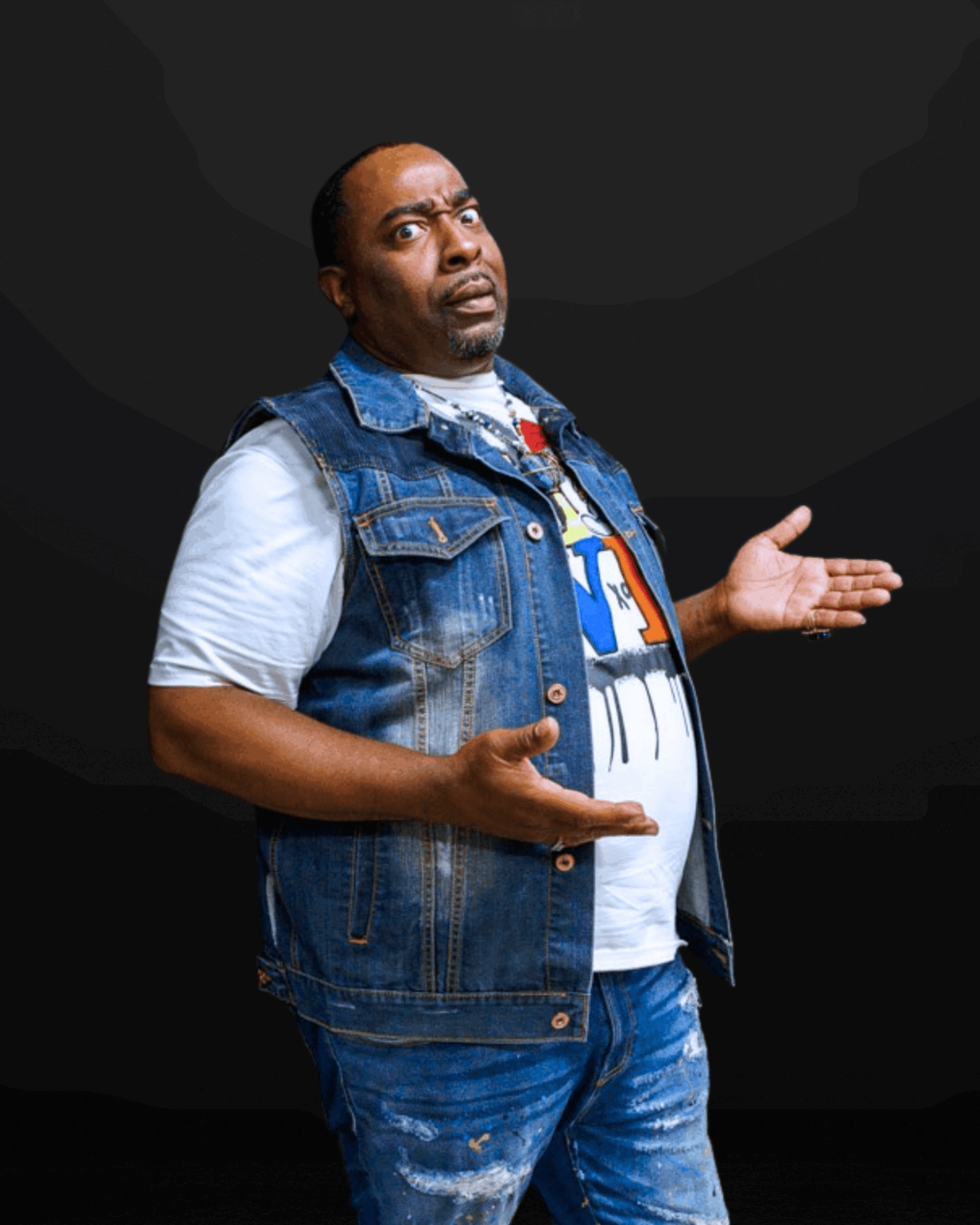 Man with a confused expression, wearing a denim vest and white t-shirt, gesturing with hands against a black background.