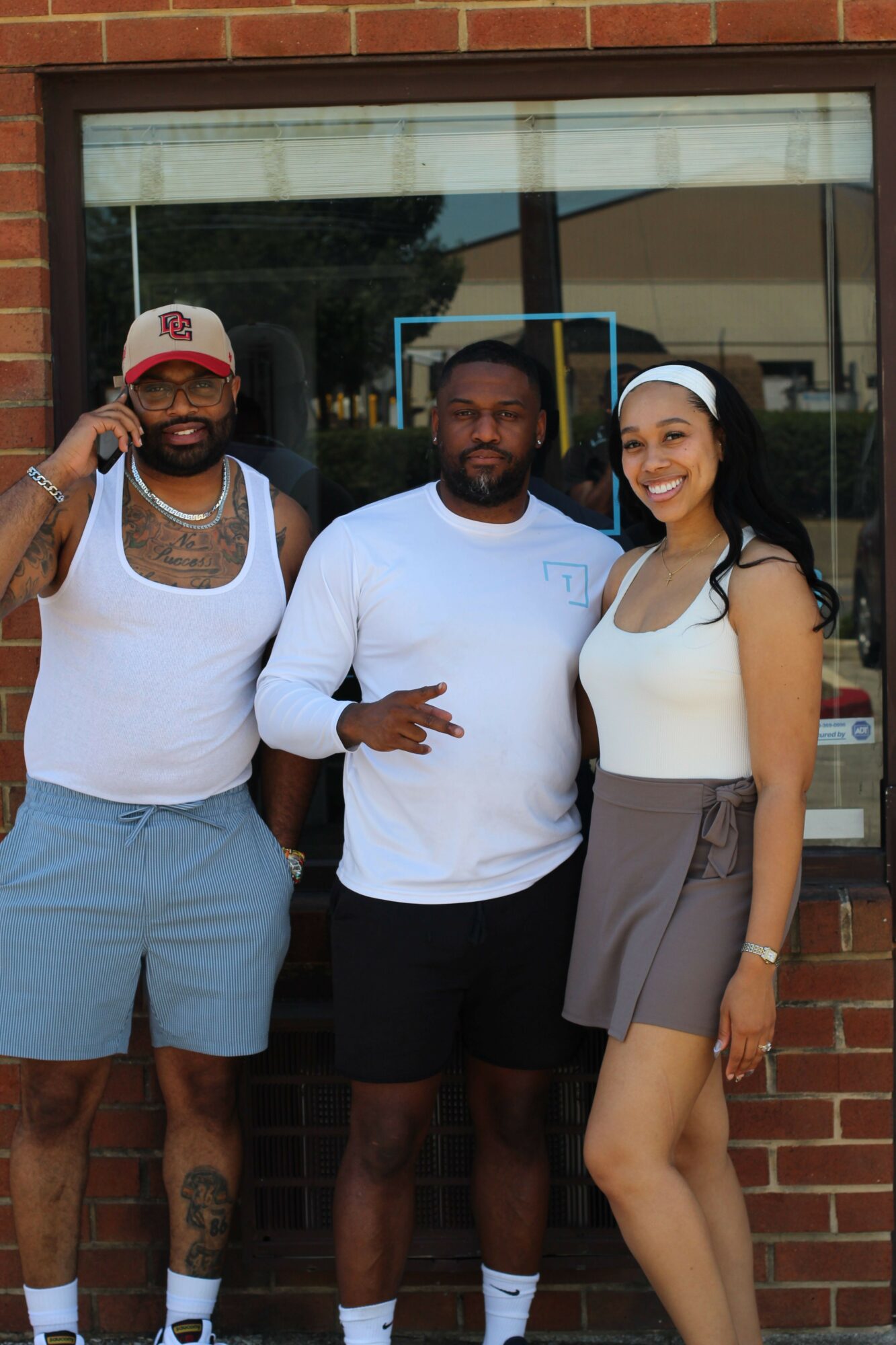 Three people standing outside a building, two men and one woman, smiling and posing for the photo.