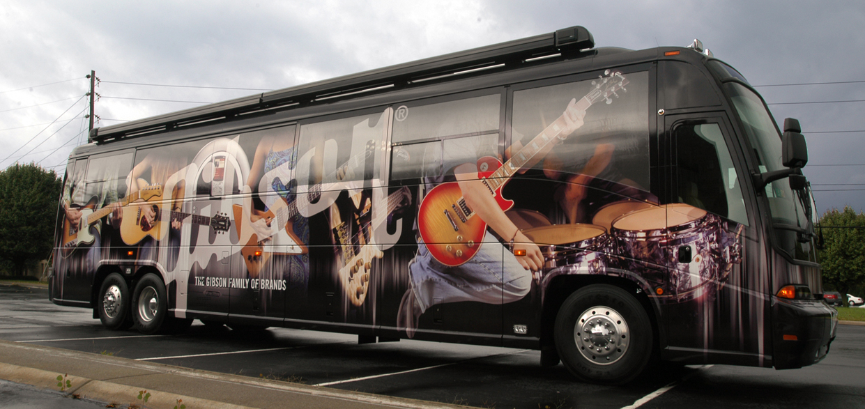 Bus with a colorful musical-themed wrap parked on the street, featuring images of guitars and musical notes.