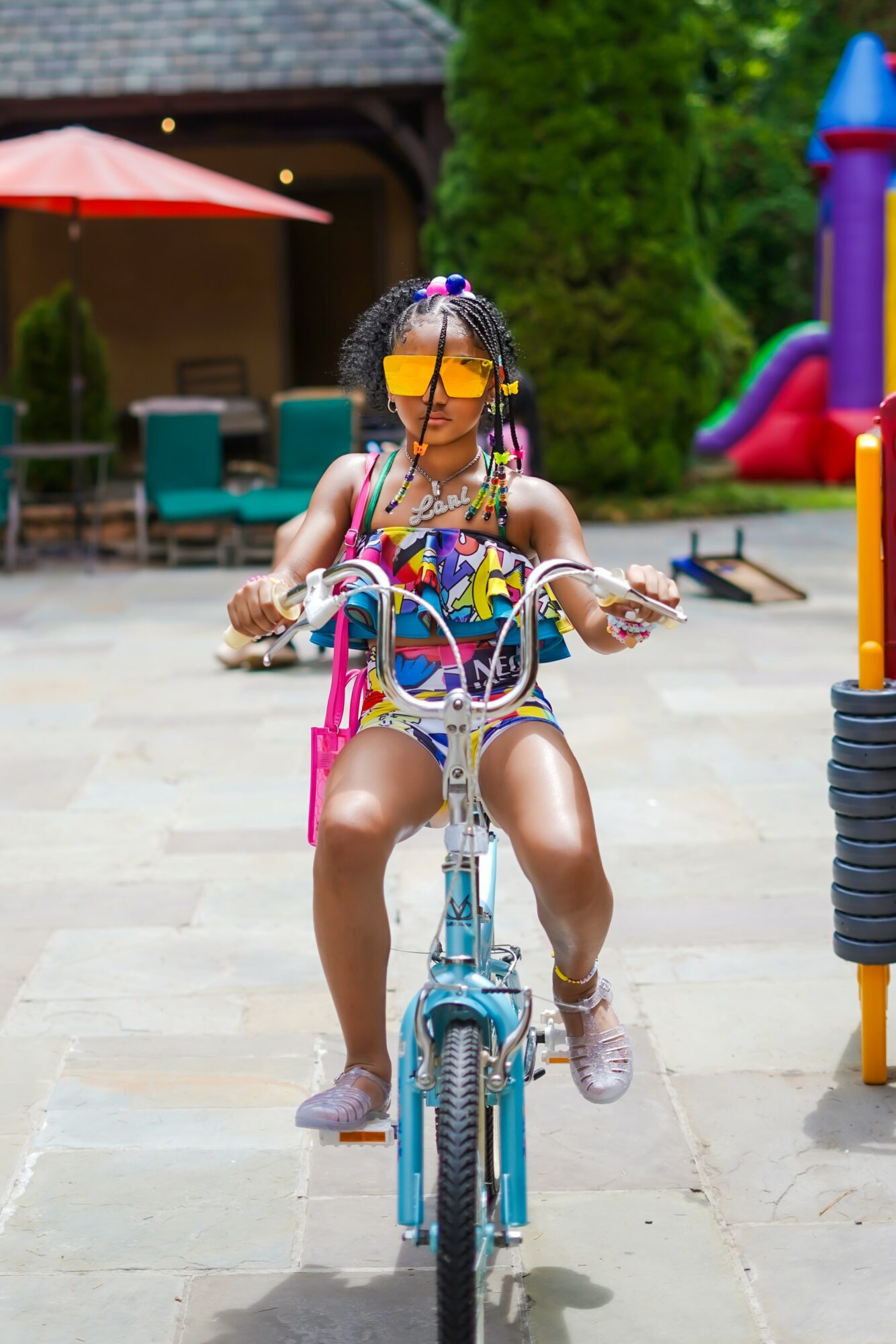 Child riding a bicycle outdoors with colorful playground equipment in background.