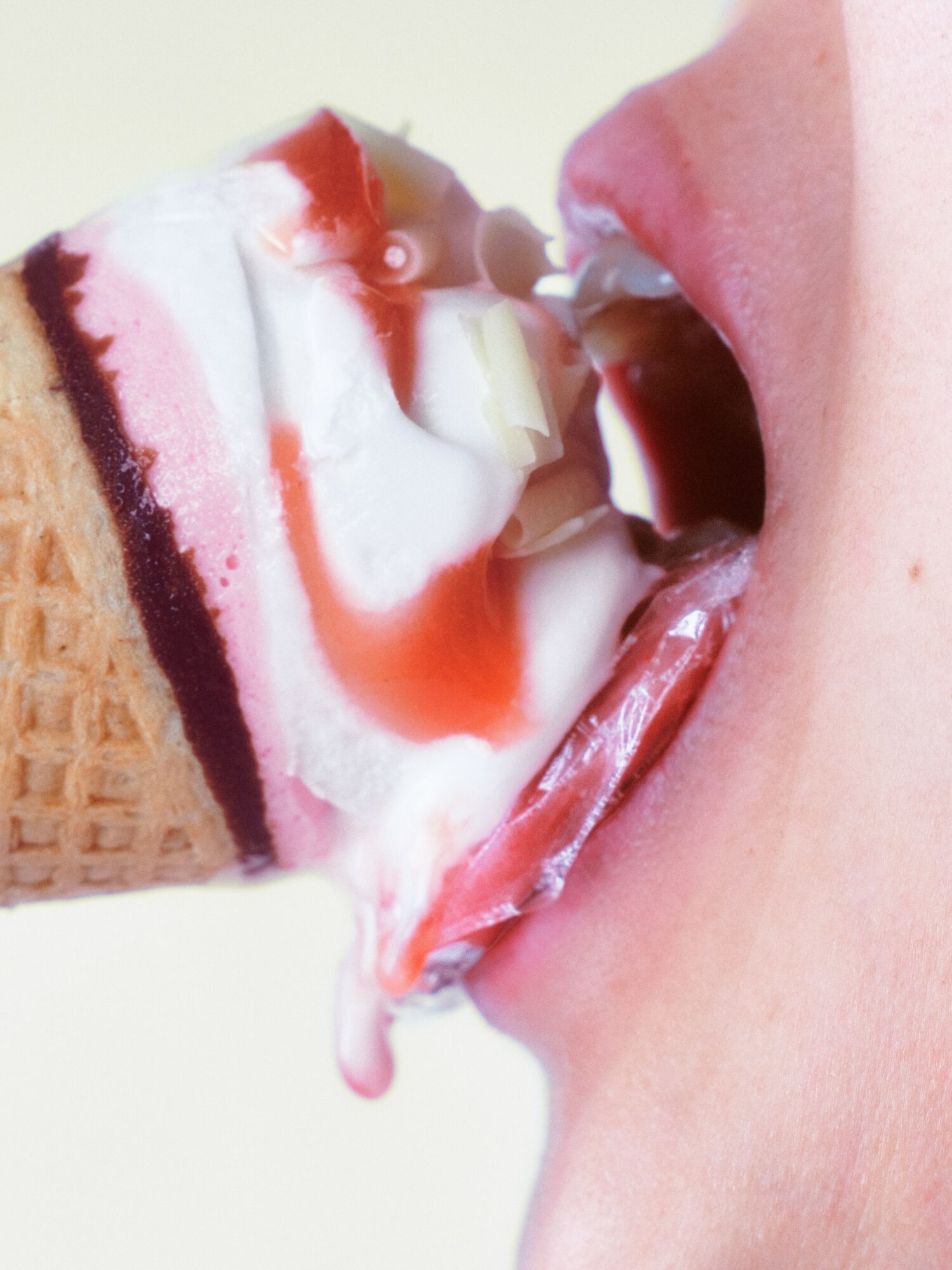 Person's mouth open with ice cream cone, melting ice cream dripping, close-up view.