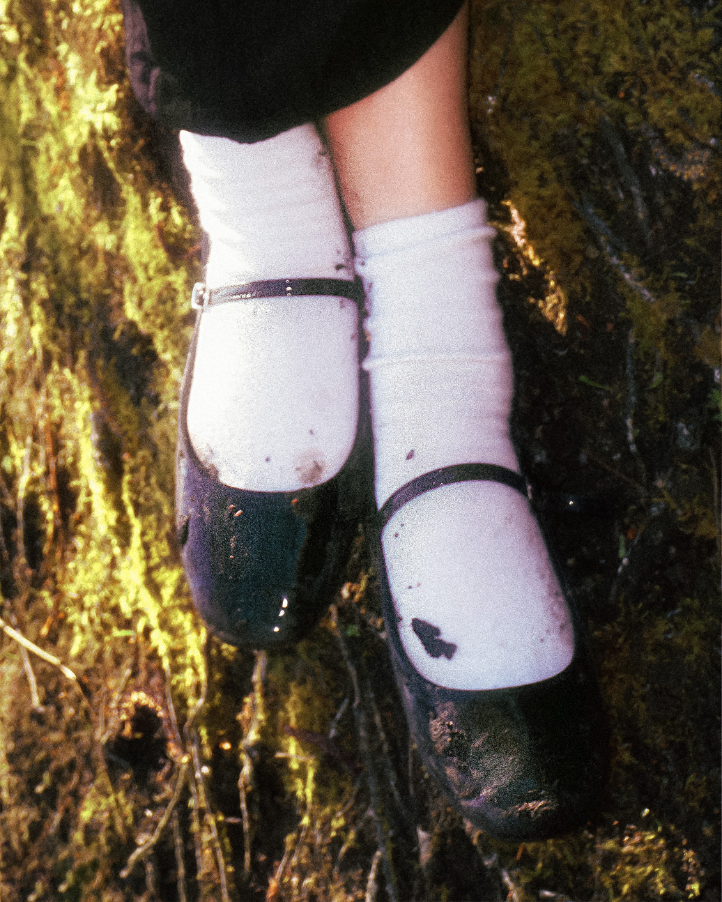 Person wearing white socks and black shoes standing on rocks outdoors, with a natural background.