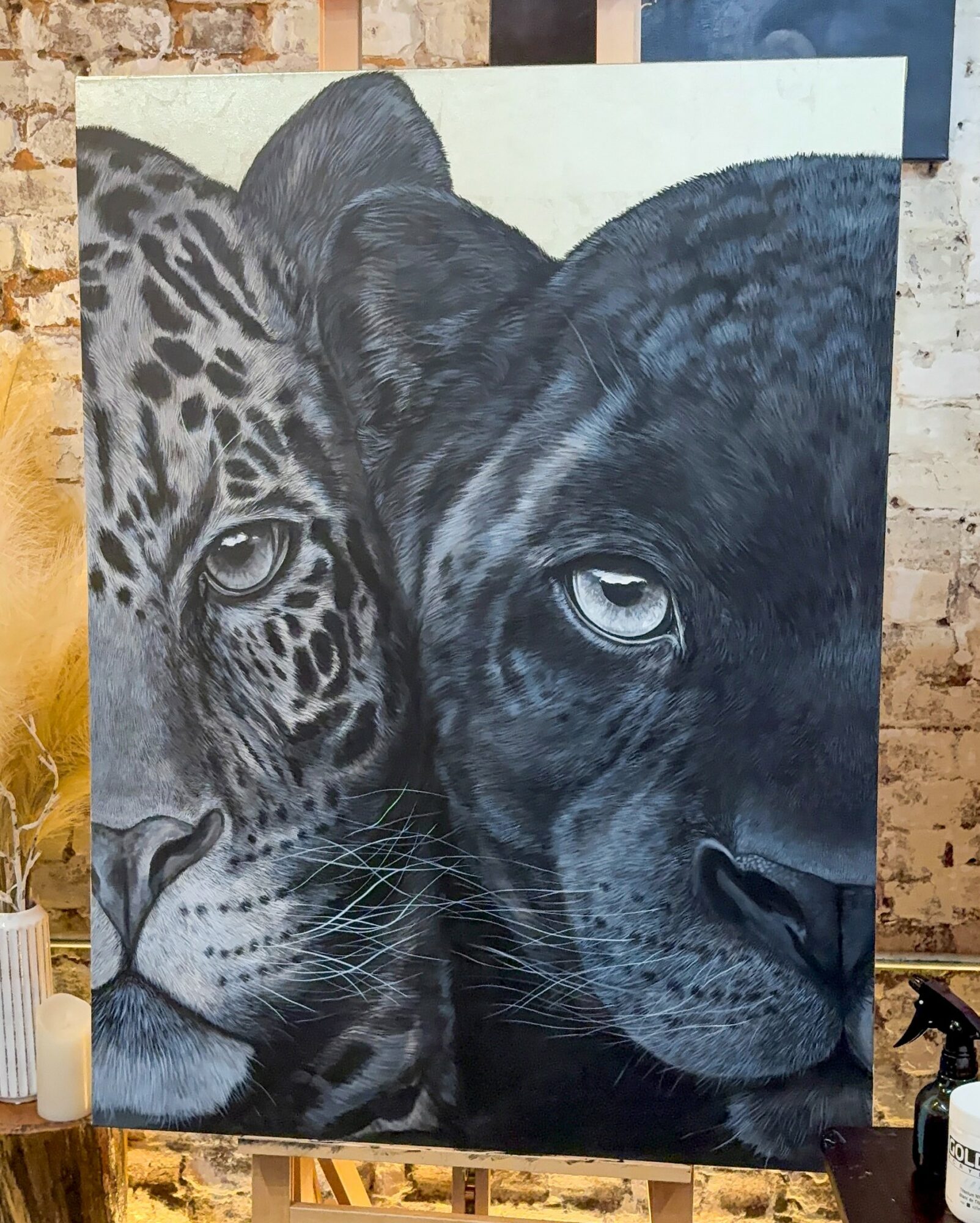 Painting of a jaguar and a black panther side by side, showing detailed facial features and fur patterns.
