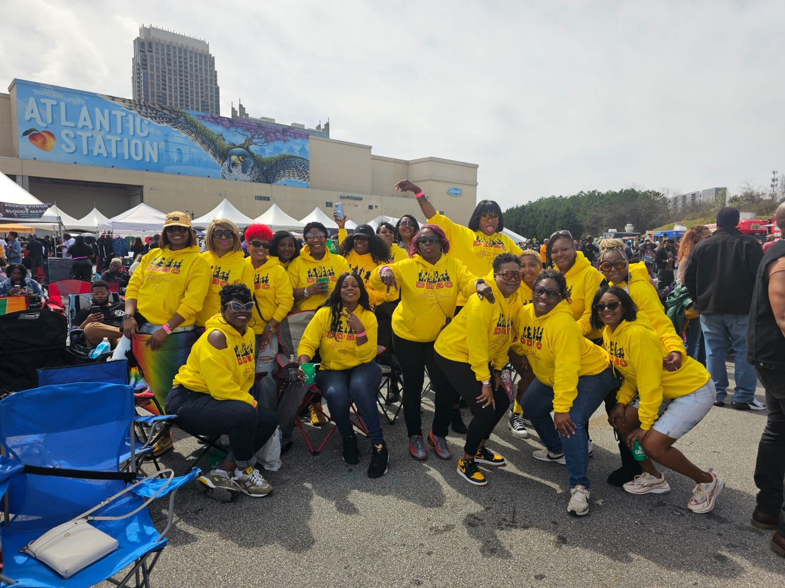 Group of people wearing yellow shirts posing outdoors in front of a building with a sign that reads 'ATLANTIC STATION'.