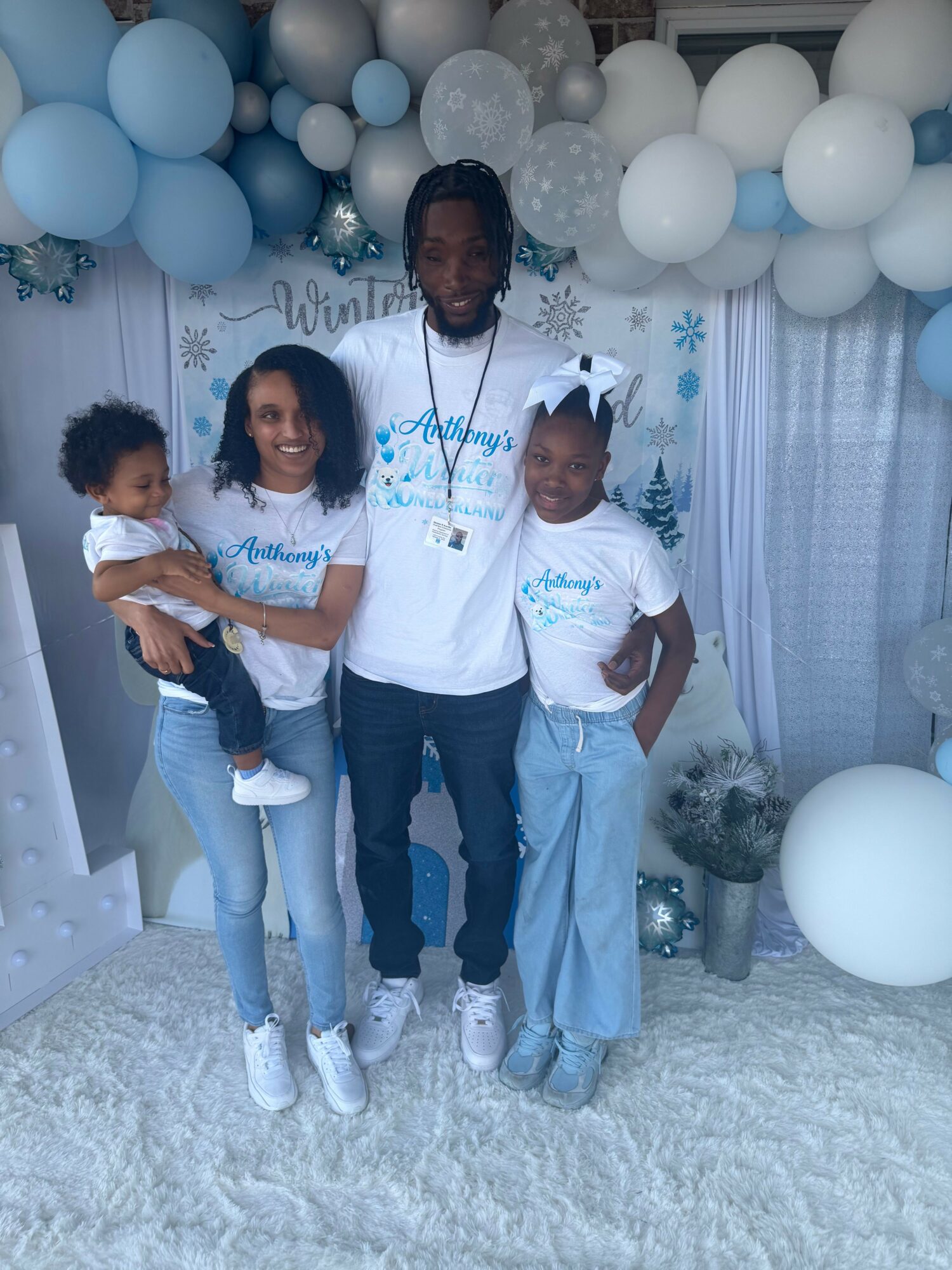 Three people standing in front of a decorated backdrop with balloons, smiling and posing for the photo.
