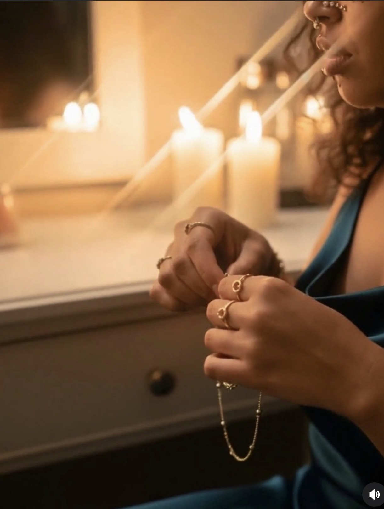 Person holding a necklace with candles and a window in the background, warm lighting, side view, indoors.