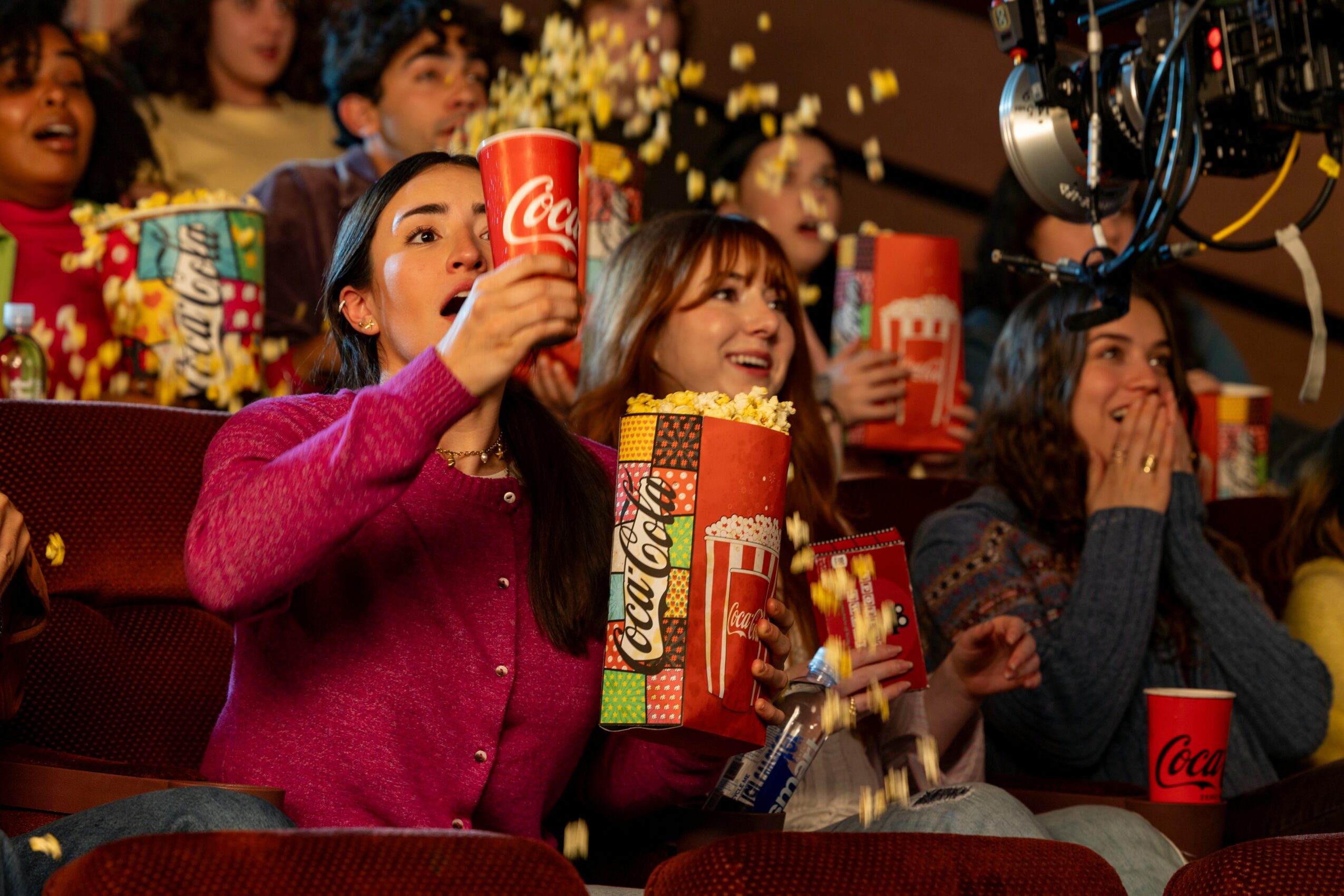 Children watching a movie with popcorn and drinks, excited and smiling in a theater, colorful background, cozy atmosphere.